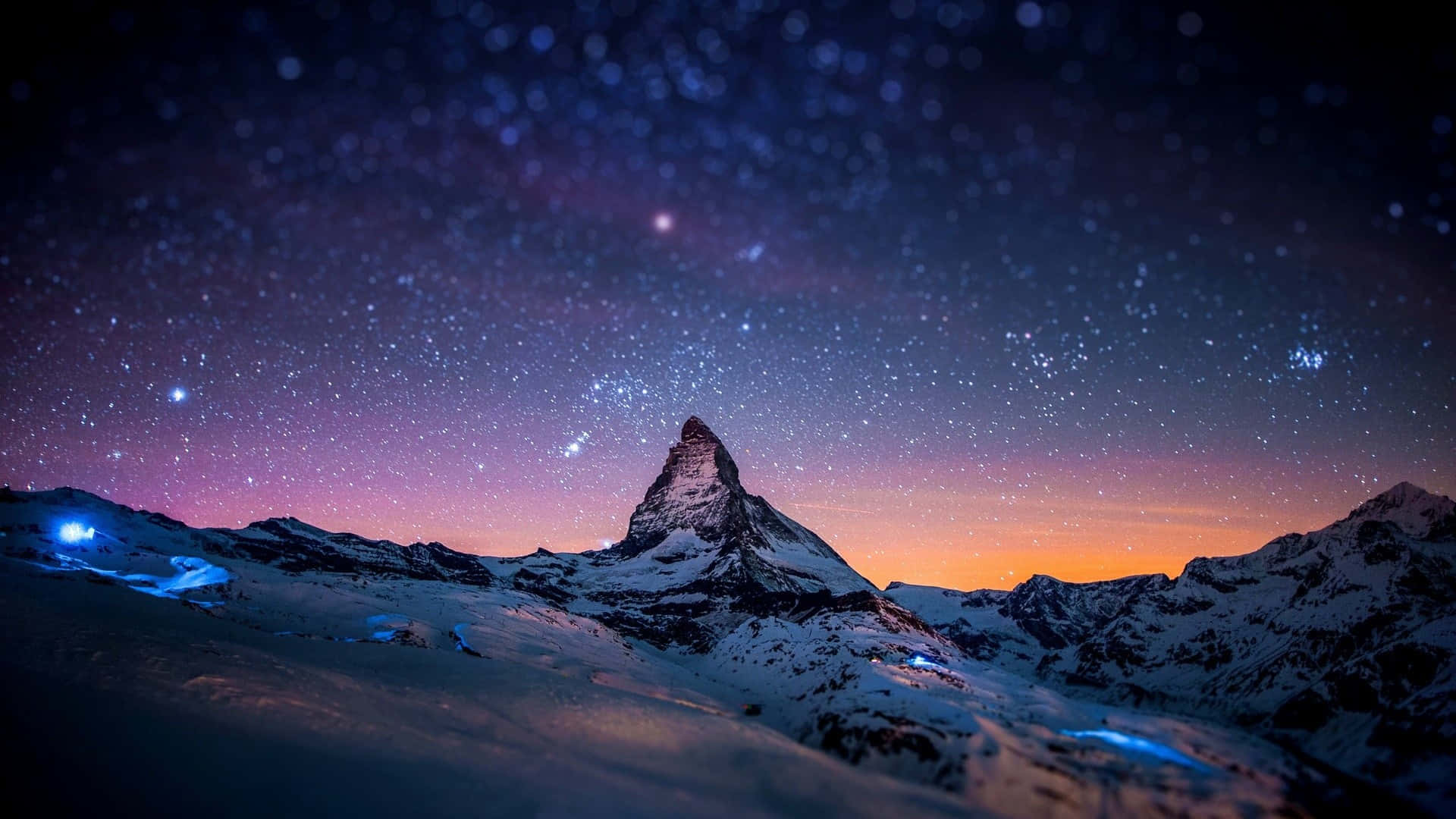 Mountain Landscape 桌布 壁紙 — 白雪覆蓋的馬特洪峰山峰剪影，襯著繁星點點的暮色天空，帶有紫橙色漸變和下方閃爍的藍光。