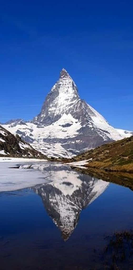 reflection 桌布 壁紙 — 白雪覆蓋的馬特洪峰山峰在清澈的藍天下巍然聳立，完美倒映在下方寧靜的高山湖泊中。