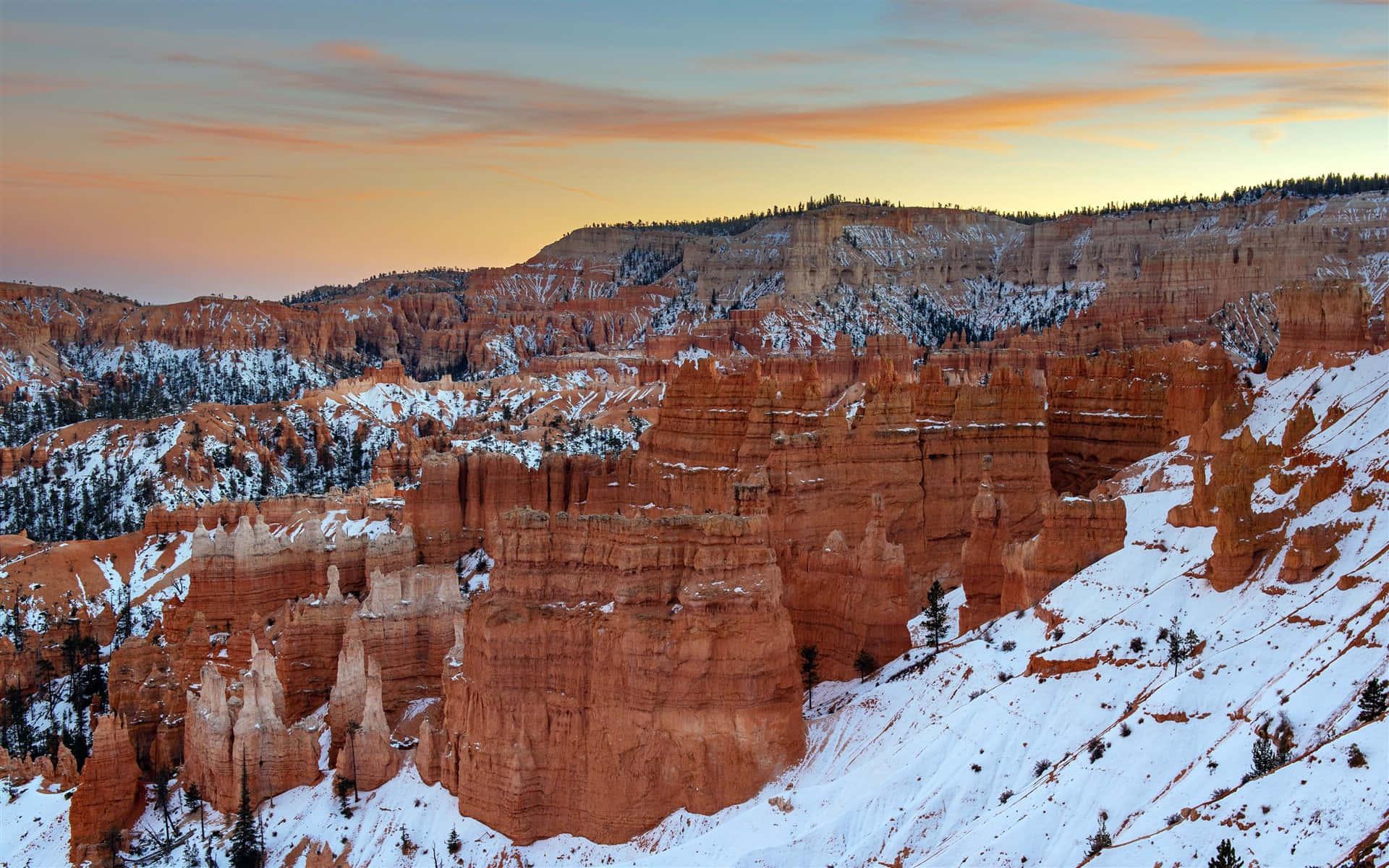 Utah 桌布 壁紙 — 白雪覆蓋紅色岩柱，在冬季峽谷中，柔和的橙色和藍色暮色天空下。