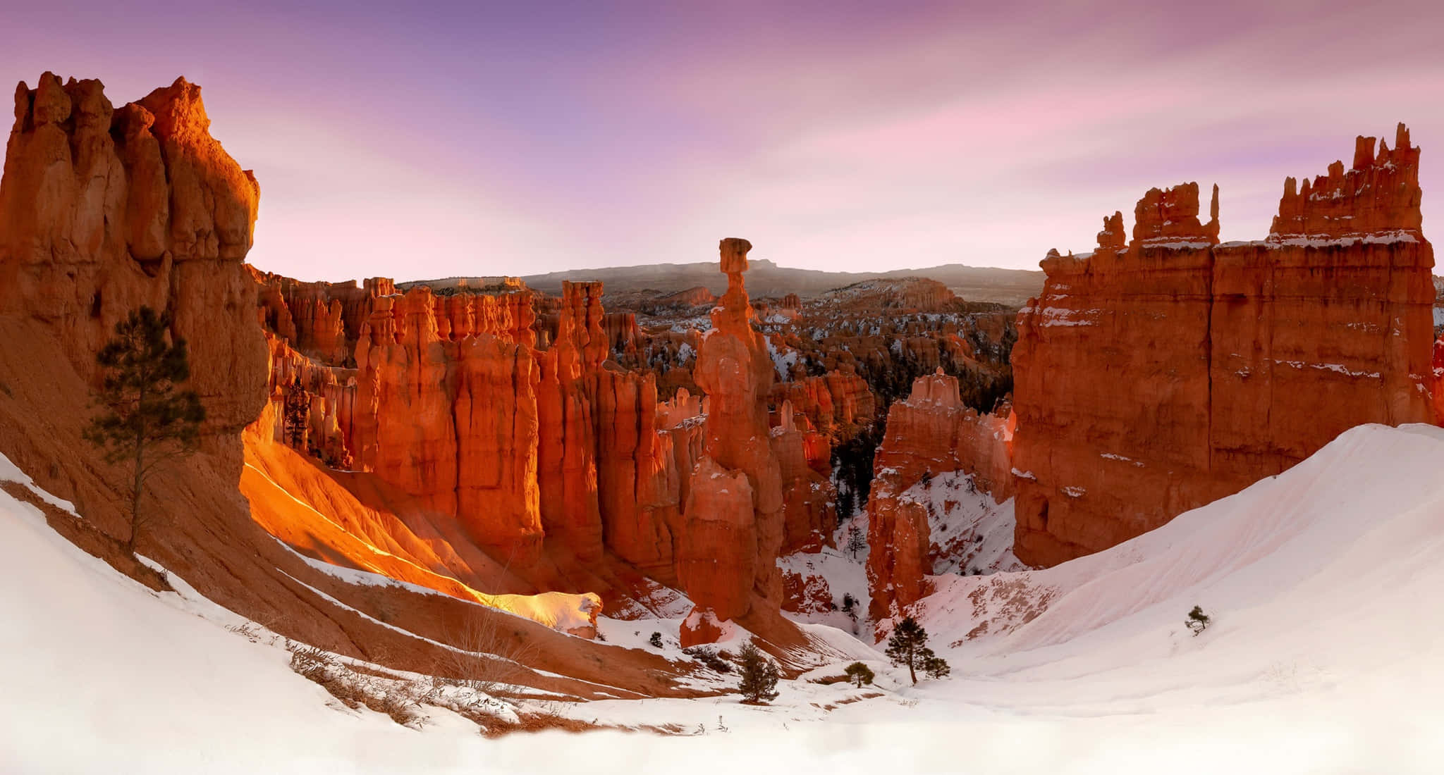 Utah 桌布 壁紙 — 白雪覆蓋紅色岩石尖塔，金色日出光芒照亮冬季峽谷牆壁。