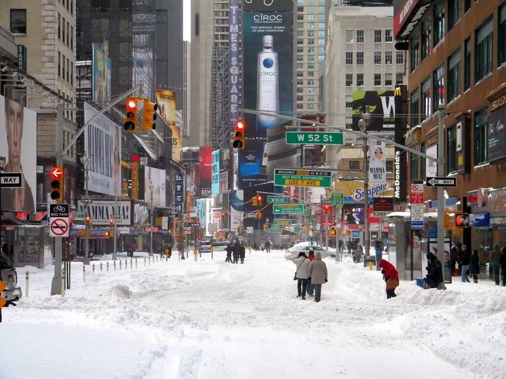 雪 桌布 壁紙 — 白雪覆蓋紐約市繁華的街道，行人在高聳的廣告牌和交通燈下穿過雪堆。