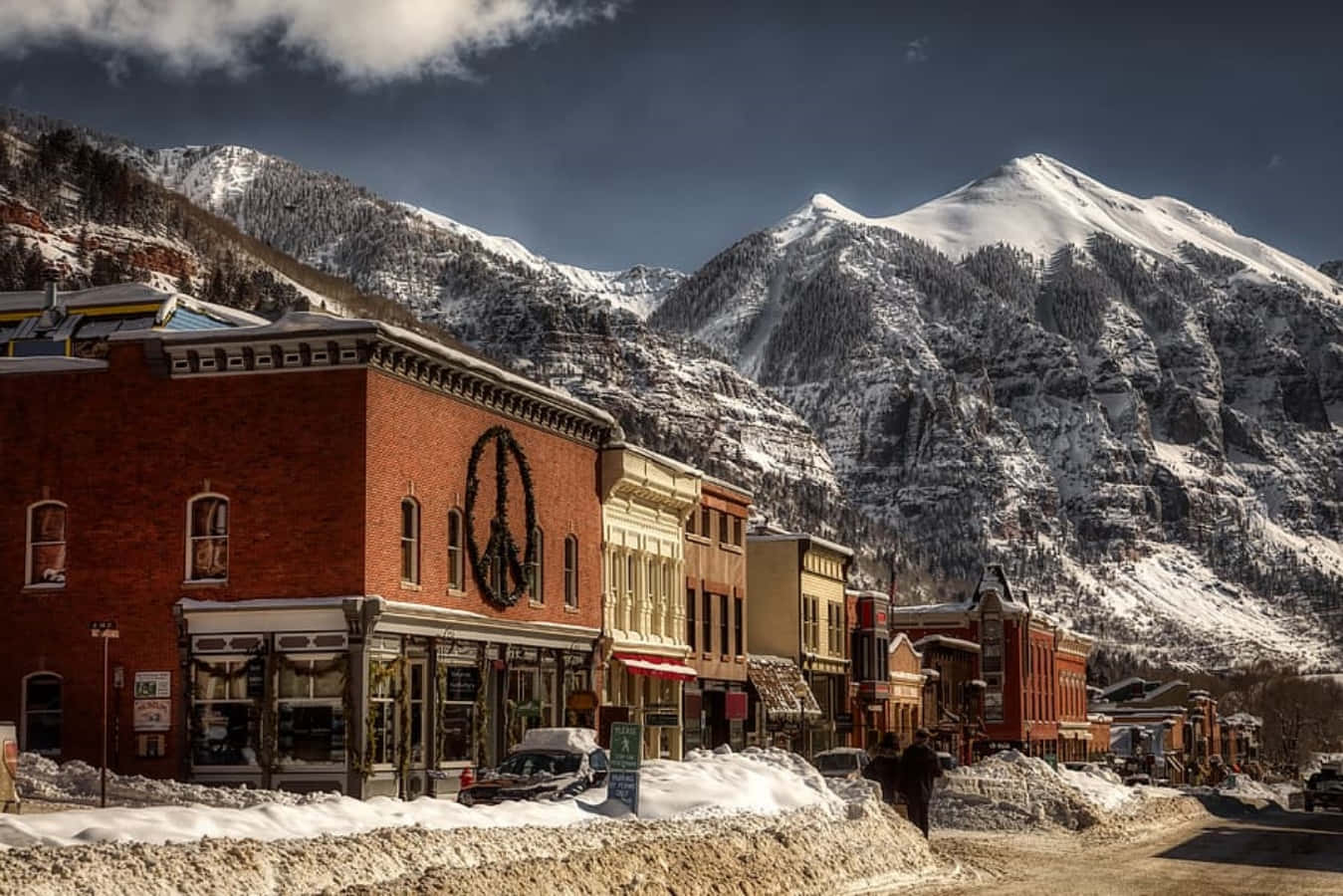 Colorado 桌布 壁紙 — 白雪覆蓋著一條古雅的山城街道，兩旁是歷史悠久的磚造建築，上方是戲劇性的多雲天空。