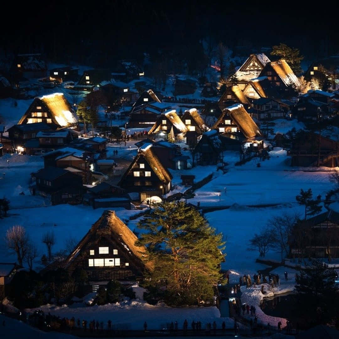 Hogsmeade 桌布 壁紙 — 白雪覆蓋著傳統茅草屋頂的房屋，山間村莊在夜空下溫暖地發光。