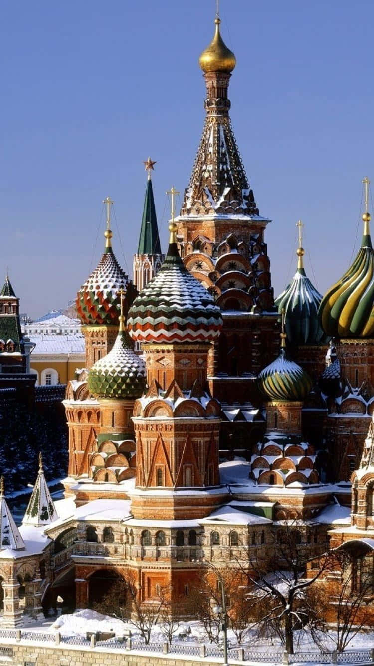 Russia 桌布 壁紙 — 白雪覆蓋著聖巴西爾大教堂標誌性的洋蔥形圓頂和紅磚牆，背景是清澈的藍色冬日天空。