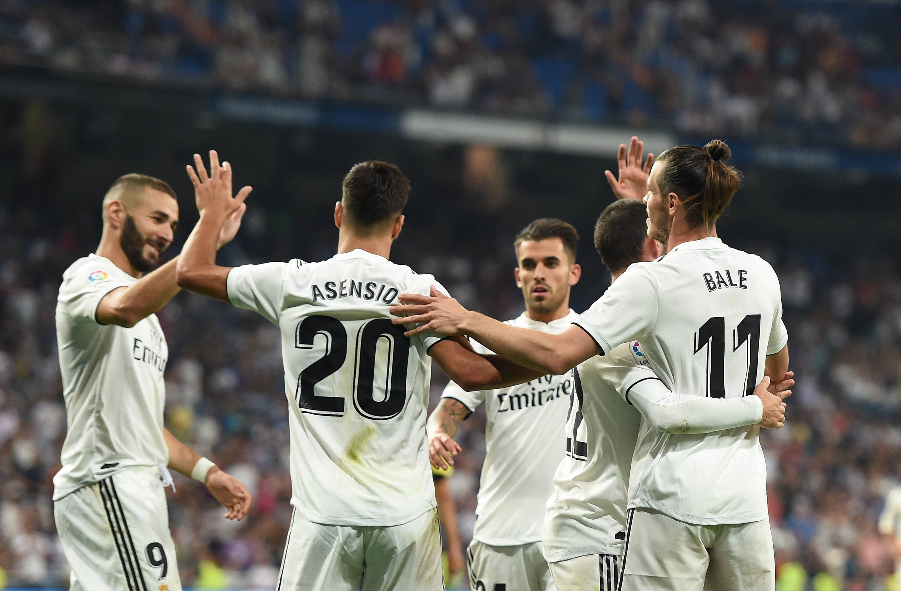 Real Madrid 4K 桌布 壁紙 — 皇家馬德里球員身穿白色球衣，在明亮的燈光下，於座無虛席的球場上以擊掌和擁抱慶祝進球。