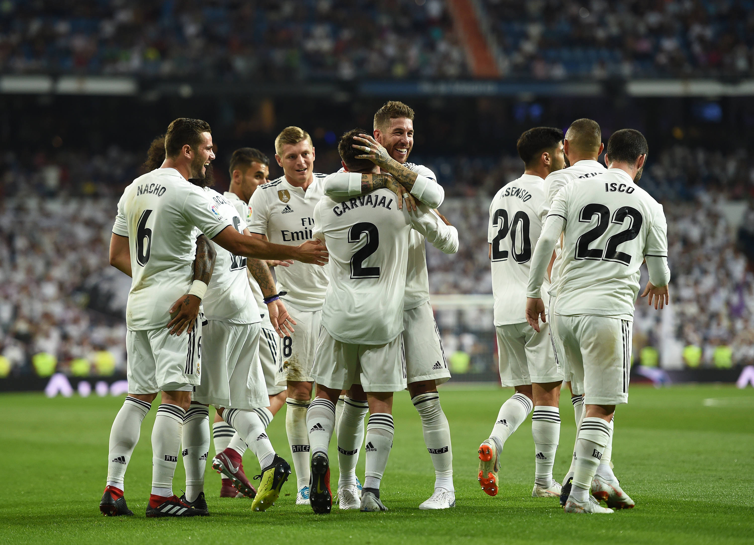 Real Madrid 4K 桌布 壁紙 — 皇家馬德里足球員身穿白色球衣，在球場燈光下於充滿活力的綠色草地上慶祝進球。