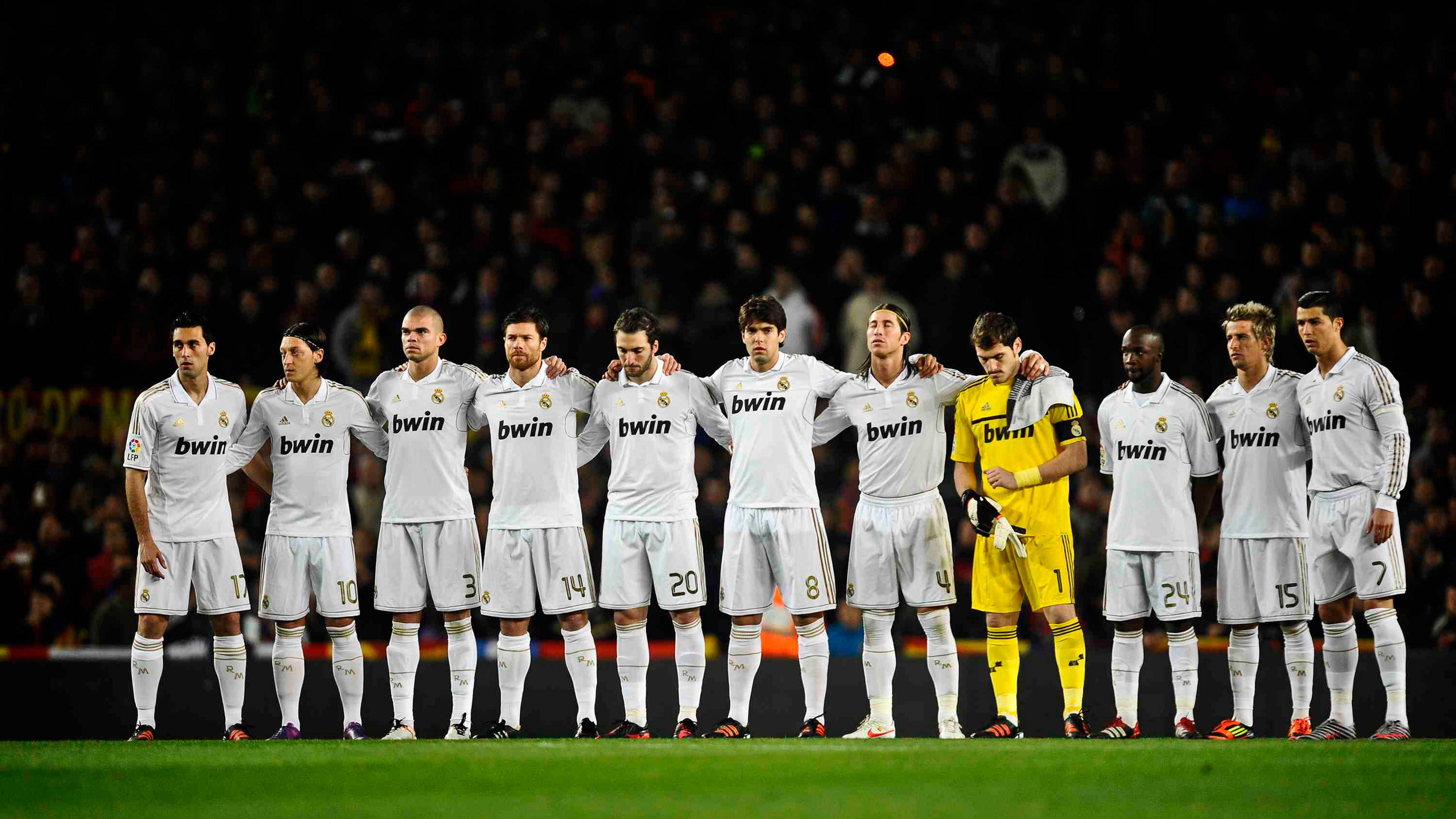 Real Madrid 4K 桌布 壁紙 — 皇家馬德里足球隊在比賽前的夜晚，在球場上排成一排，互相搭著肩膀。