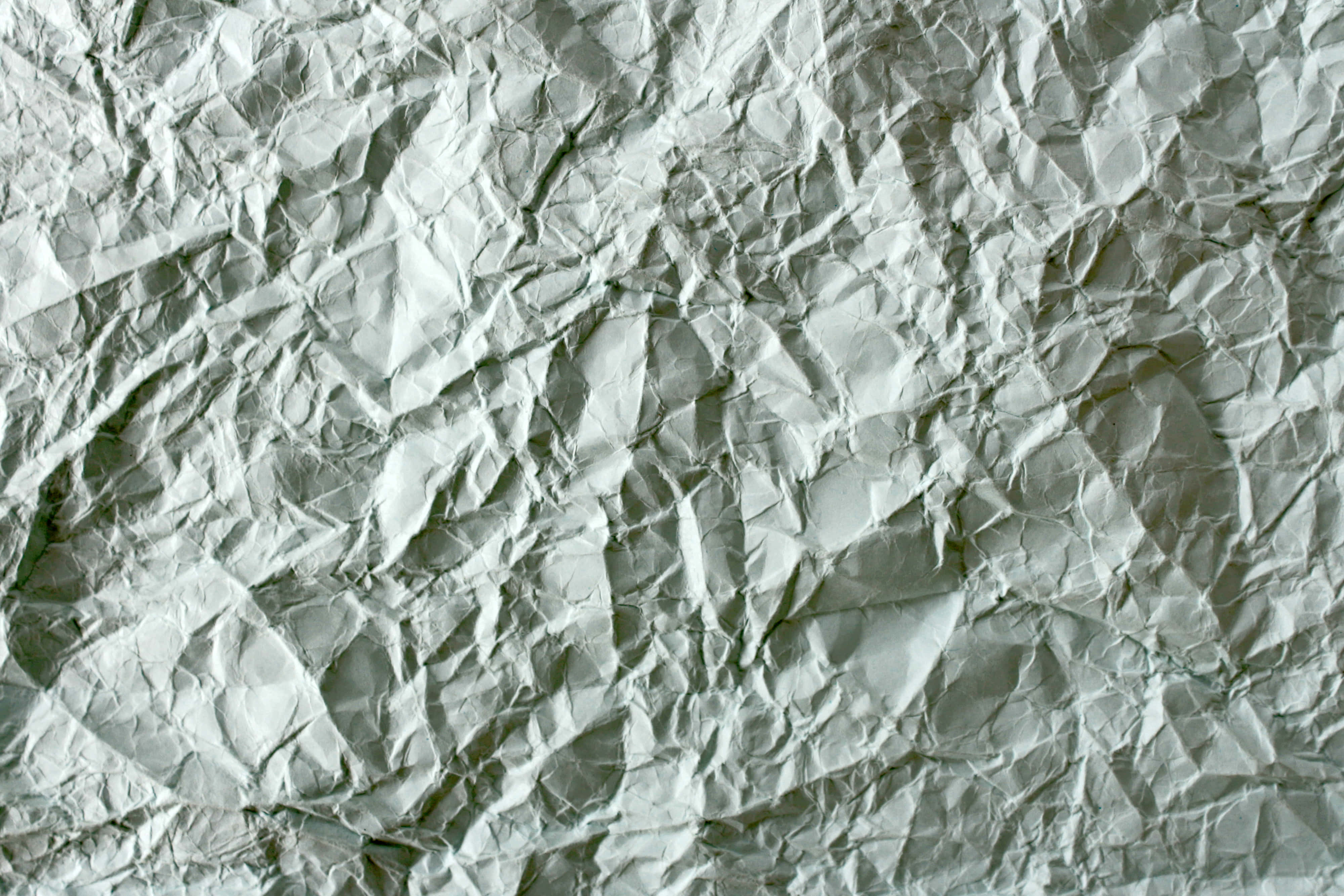 Paper Texture 桌布 壁紙 — 皺巴巴白紙的特寫，帶有深摺痕和柔和陰影，營造出紋理化的抽象表面。