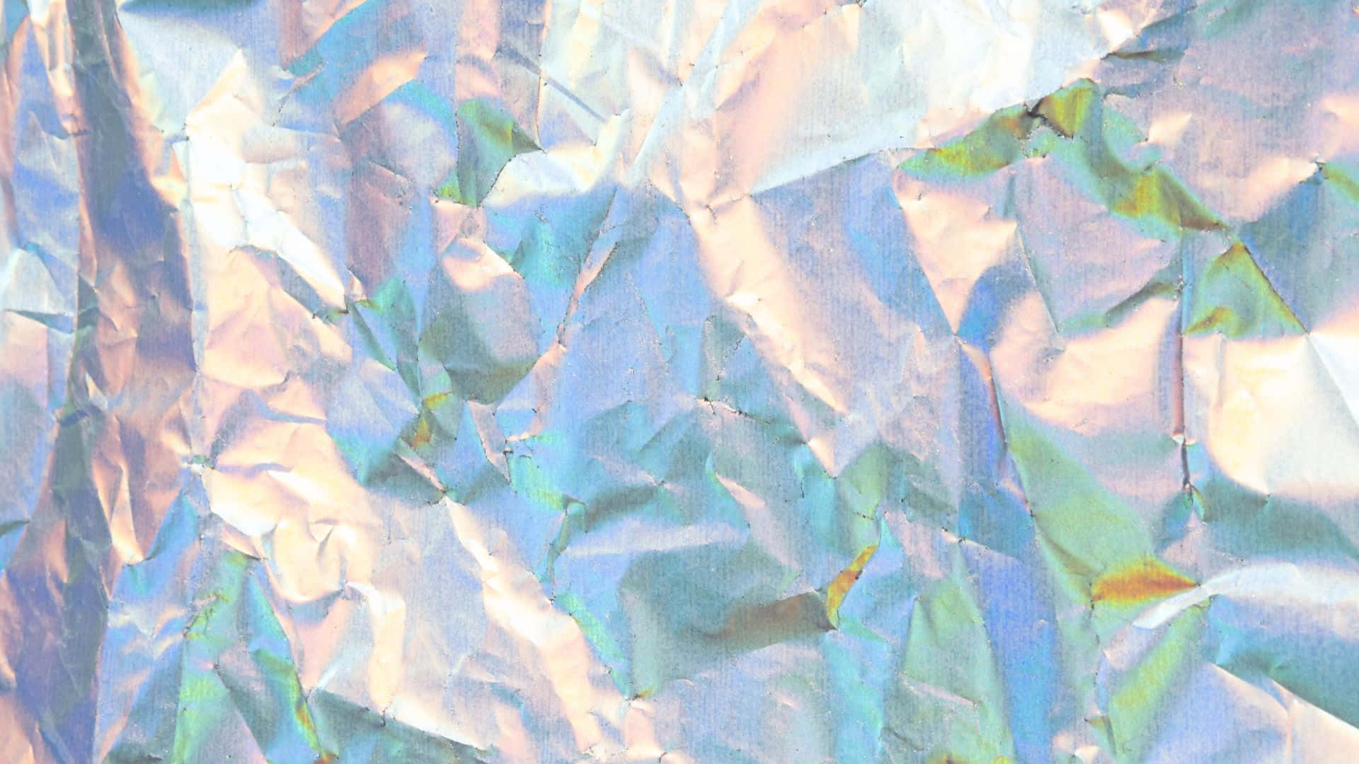 Textured 桌布 壁紙 — 皺巴巴的彩虹色箔紙特寫，在紋理化的抽象圖案中反射出變化的藍色、粉紅色和綠色。