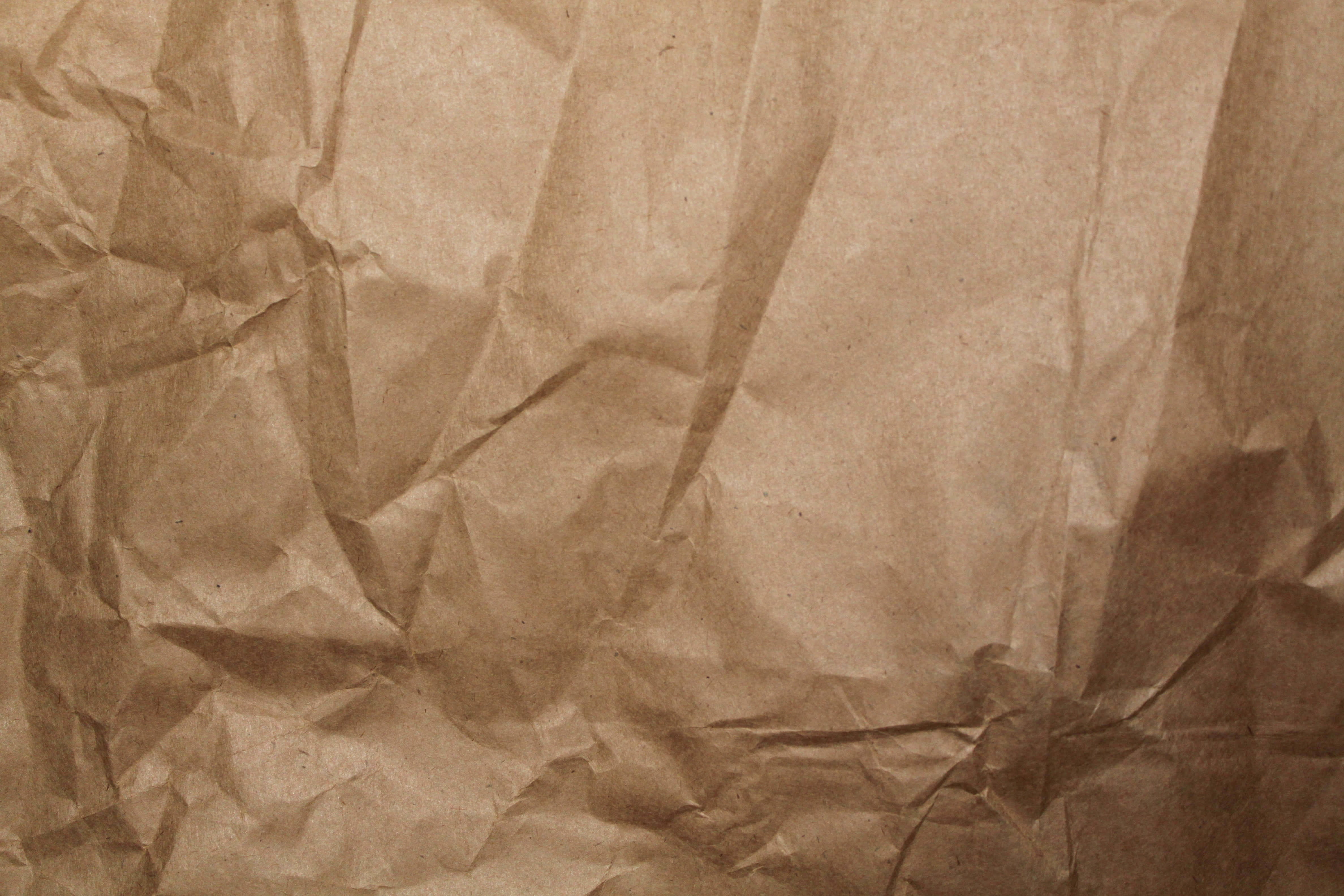 Brown Paper 桌布 壁紙 — 皺巴巴的棕色紙張特寫，帶有深摺痕和柔和陰影，營造出觸感紋理表面。