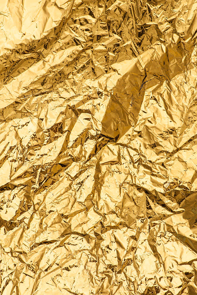 Metallic Gold 桌布 壁紙 — 皺巴巴的金箔特寫，帶有銳利的摺痕和反射亮點，營造出豪華的紋理表面。