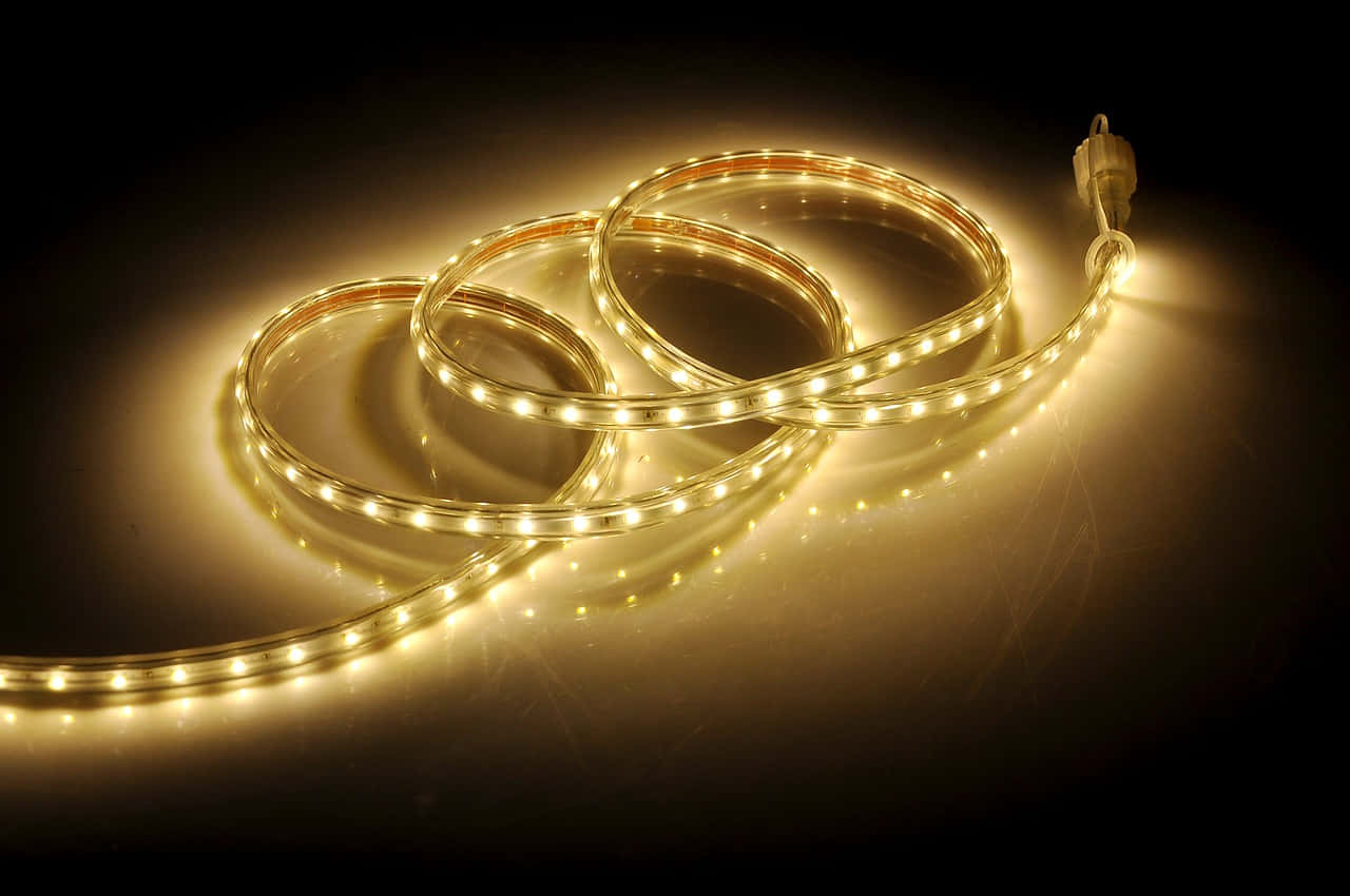 Led Light 桌布 壁紙 — 盤繞的暖白色LED燈帶在深色反光表面上柔和發光，投射出金色光暈。