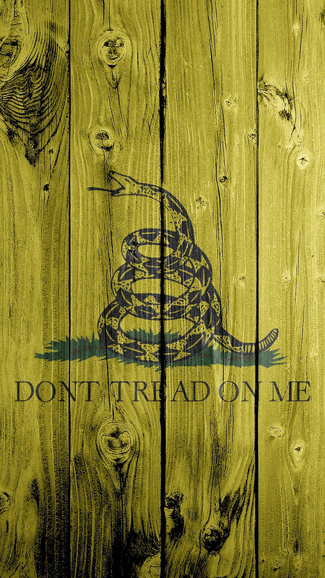 Gadsden Flag 桌布 壁紙 — 盤繞的響尾蛇，上面有'DON'T TREAD ON ME'文字，以深藍色繪在風化的黃色木板上。