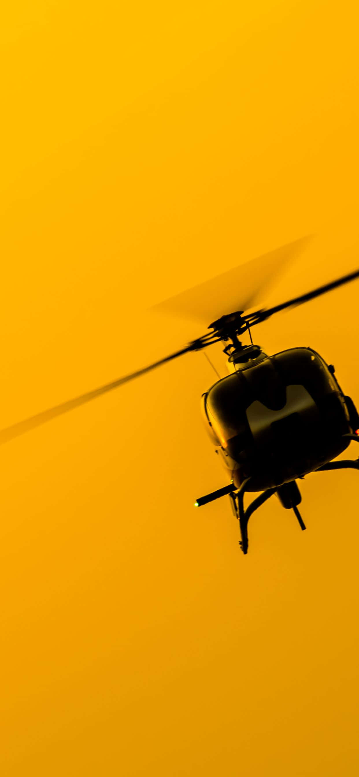 iPhone Xs Max Helicopters 桌布 壁紙 — 直升機剪影在日落時分翱翔於充滿活力的金色天空。