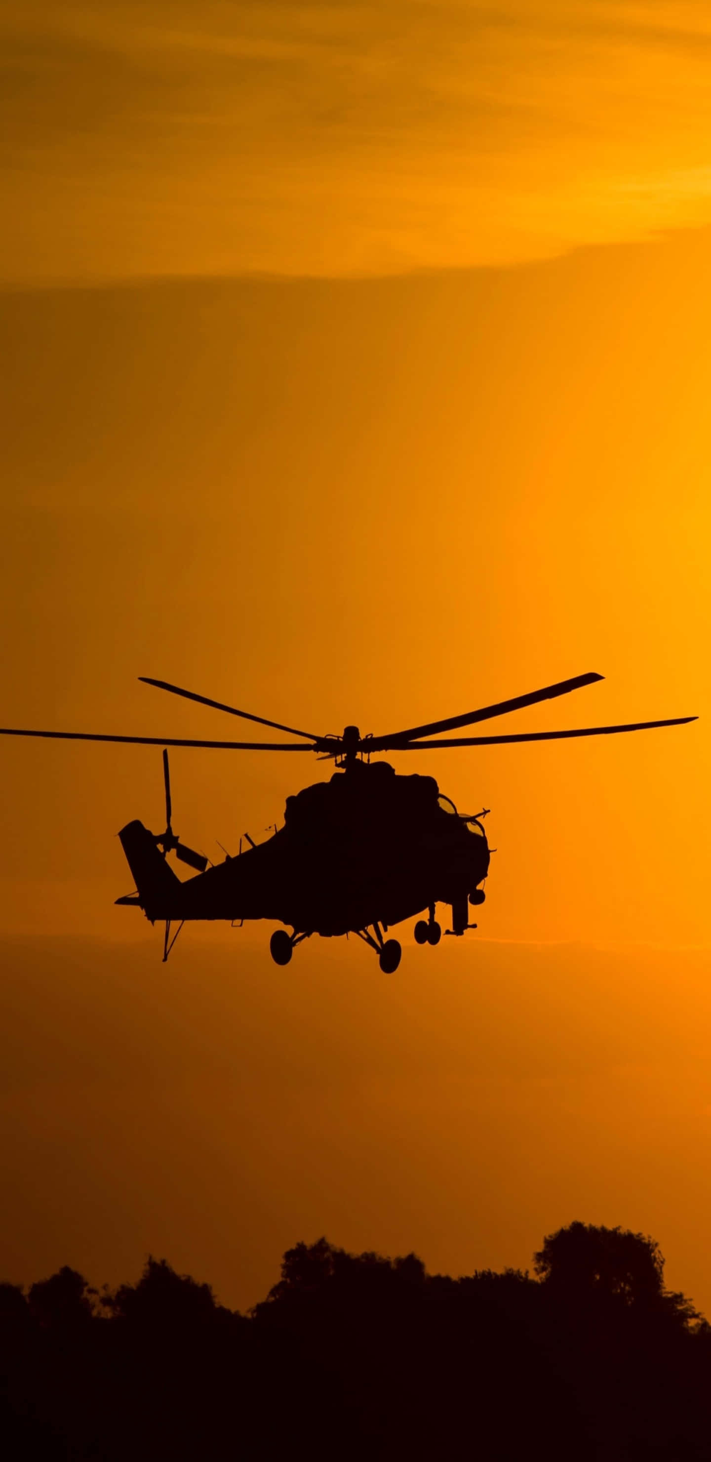 Helicopter 桌布 壁紙 — 直升機剪影在火紅橙色的日落天空中翱翔，下方是黑暗的樹線。