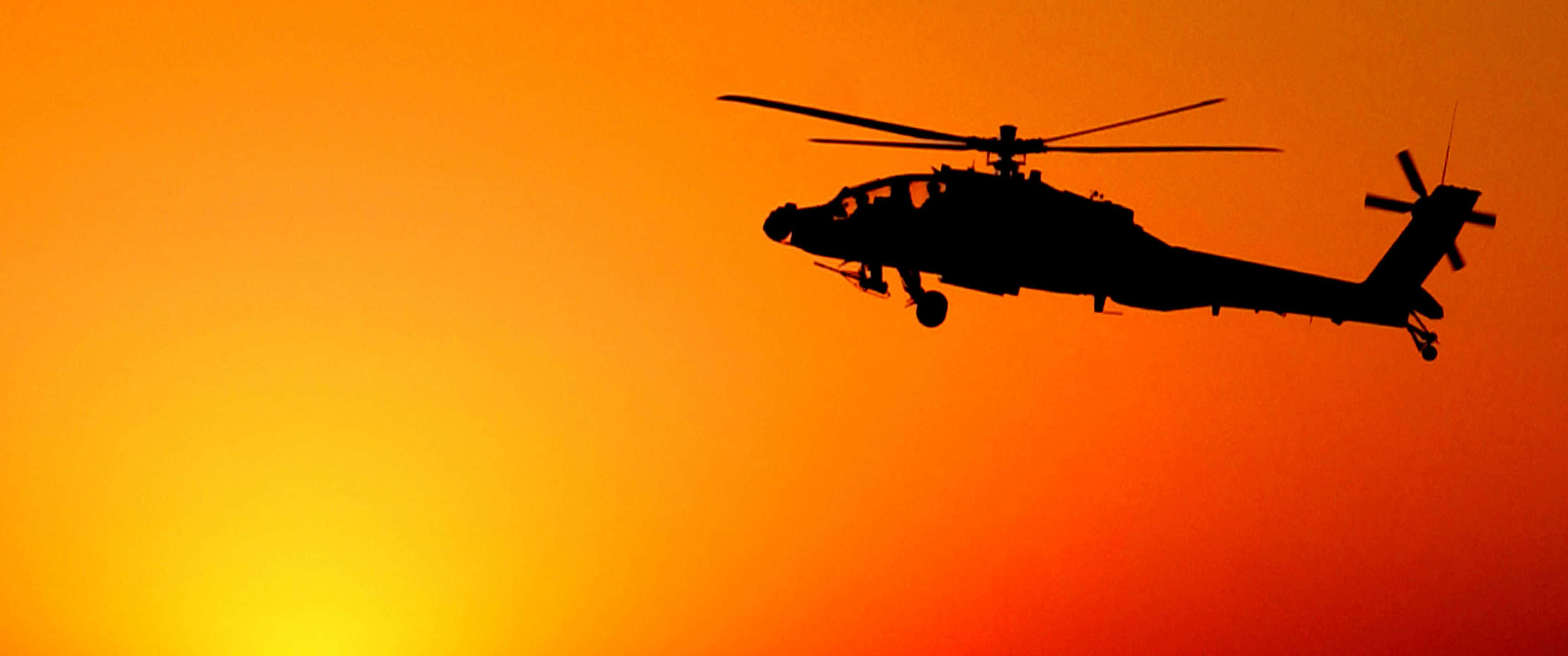 3440x1440p Helicopters 桌布 壁紙 — 直升機的剪影在火紅的橙色日落天空中翱翔。