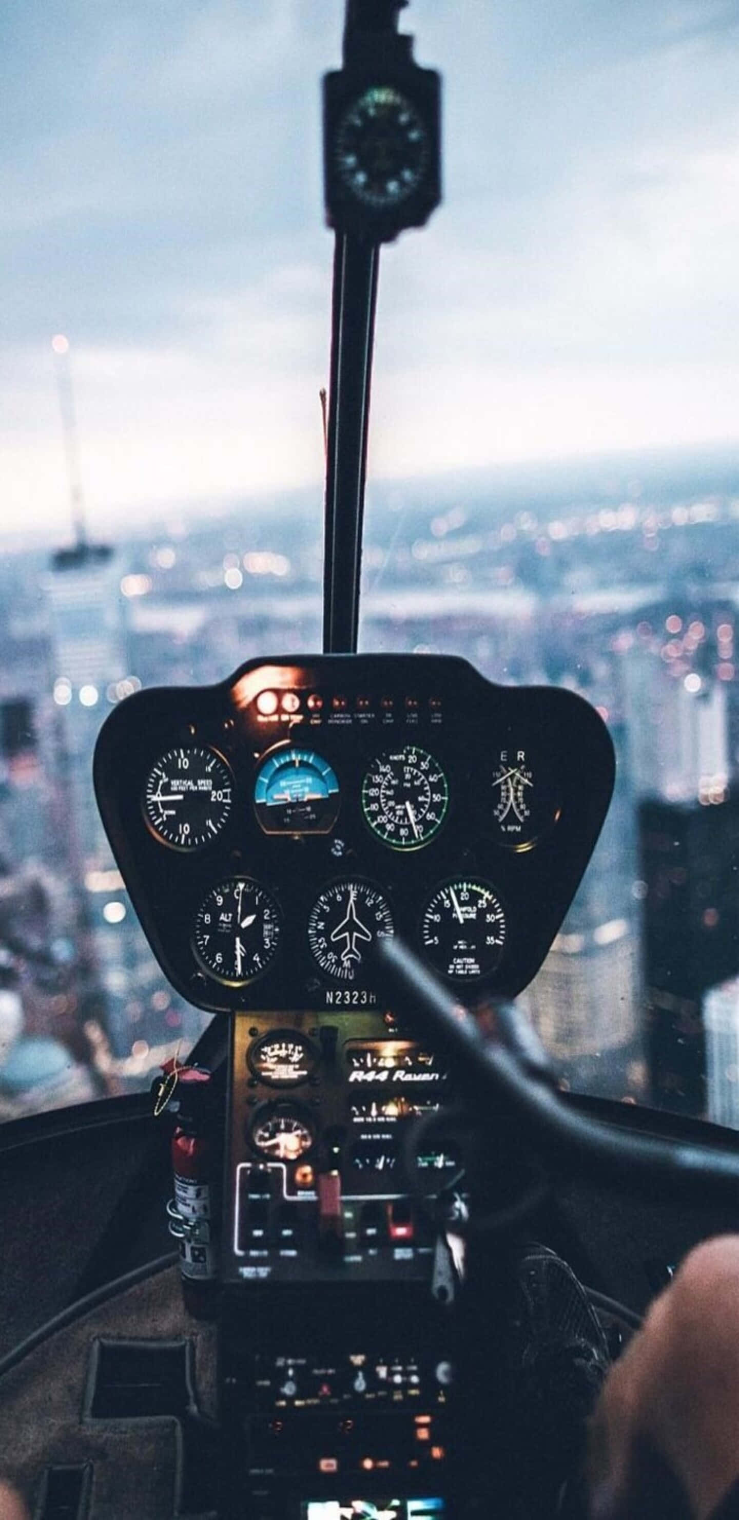 Helicopter 桌布 壁紙 — 直升機駕駛艙儀表板帶有發光錶盤，俯瞰暮色中廣闊的城市景觀。