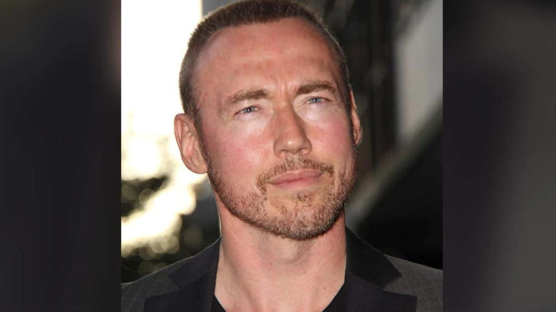 Kevin Durand 桌布 壁紙 — 短髮鬍渣男士的特寫肖像，穿著深色西裝外套。