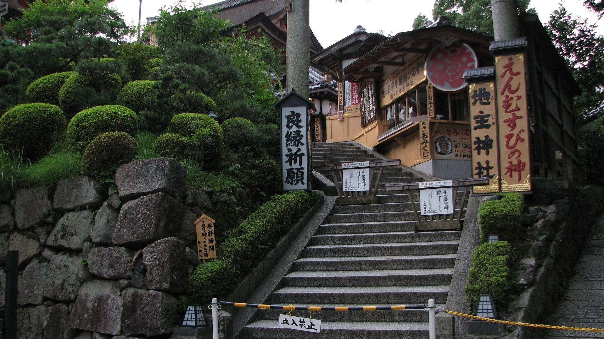 京都 桌布 壁紙 — 石階向上延伸至一座傳統日本神社，四周環繞著修剪整齊的綠植和長滿苔蘚的岩石。