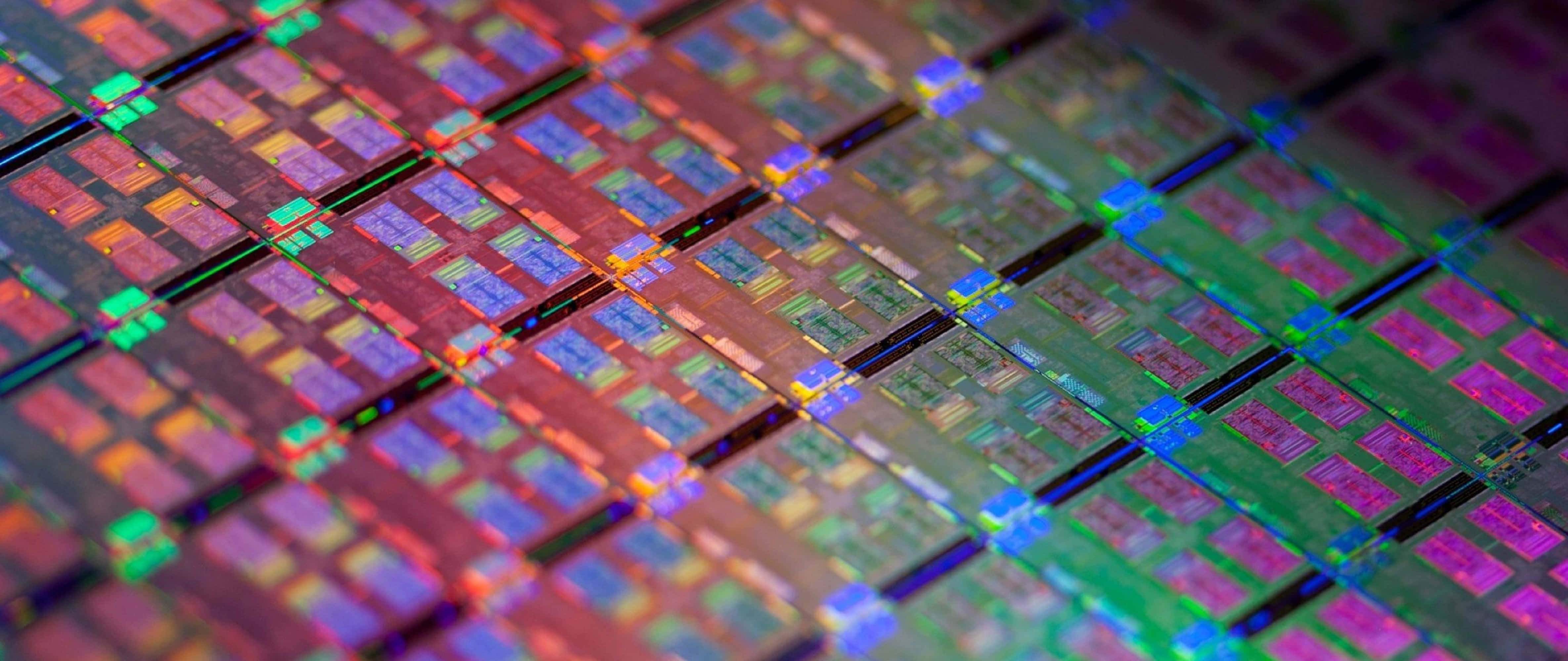 4K Processor 桌布 壁紙 — 矽晶圓的特寫，上面有彩色微晶片在光線下發光。