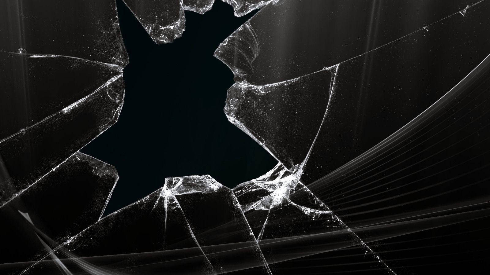 Broken Computer Screen 桌布 壁紙 — 破碎的玻璃碎片從中央裂縫向四周輻射，背景為深色，帶有光條。