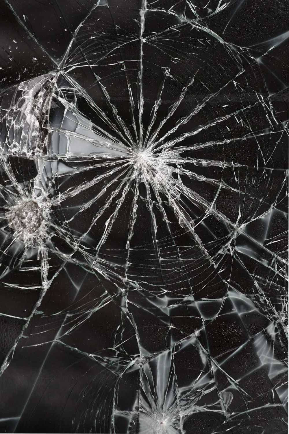 broken monitor 桌布 壁紙 — 破碎的玻璃表面，複雜的裂紋從撞擊點向四周擴散，背景為深色。