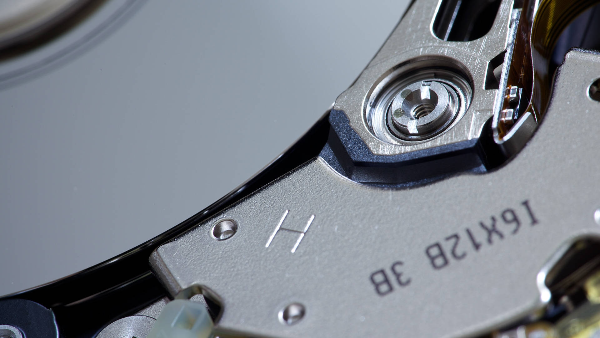 Hard Drive 桌布 壁紙 — 硬碟內部機制的特寫，顯示金屬碟片和帶有刻印規格的讀寫頭。