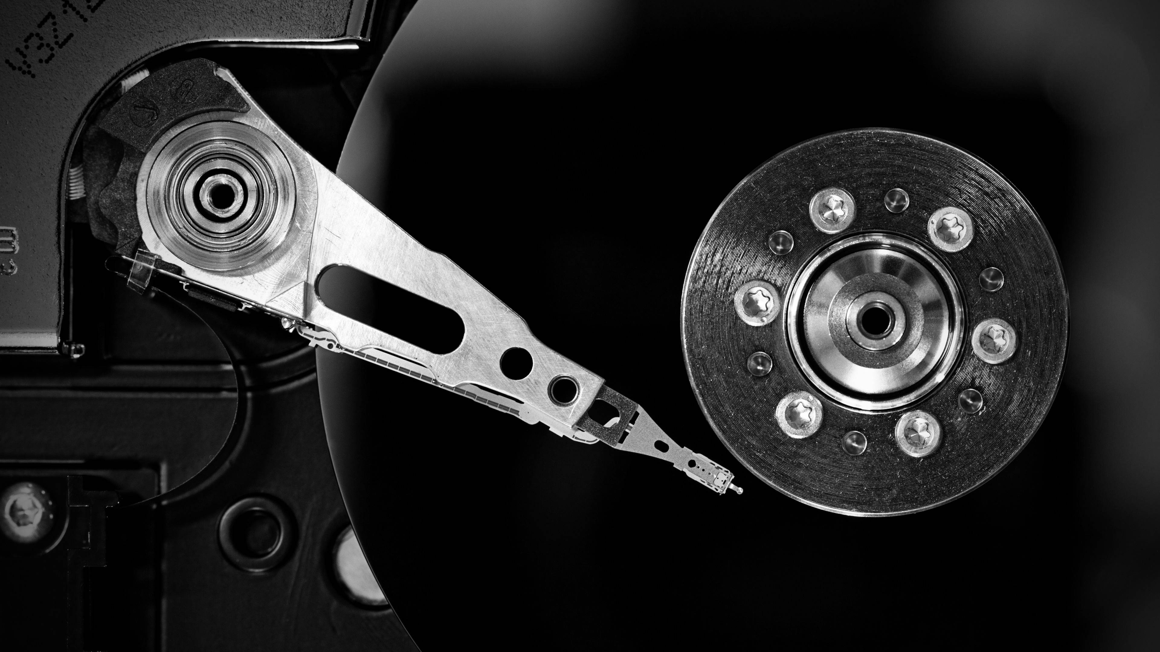 Hard Drive 桌布 壁紙 — 硬碟讀寫頭在旋轉碟片上懸浮的黑白特寫，帶有銳利的金屬細節。