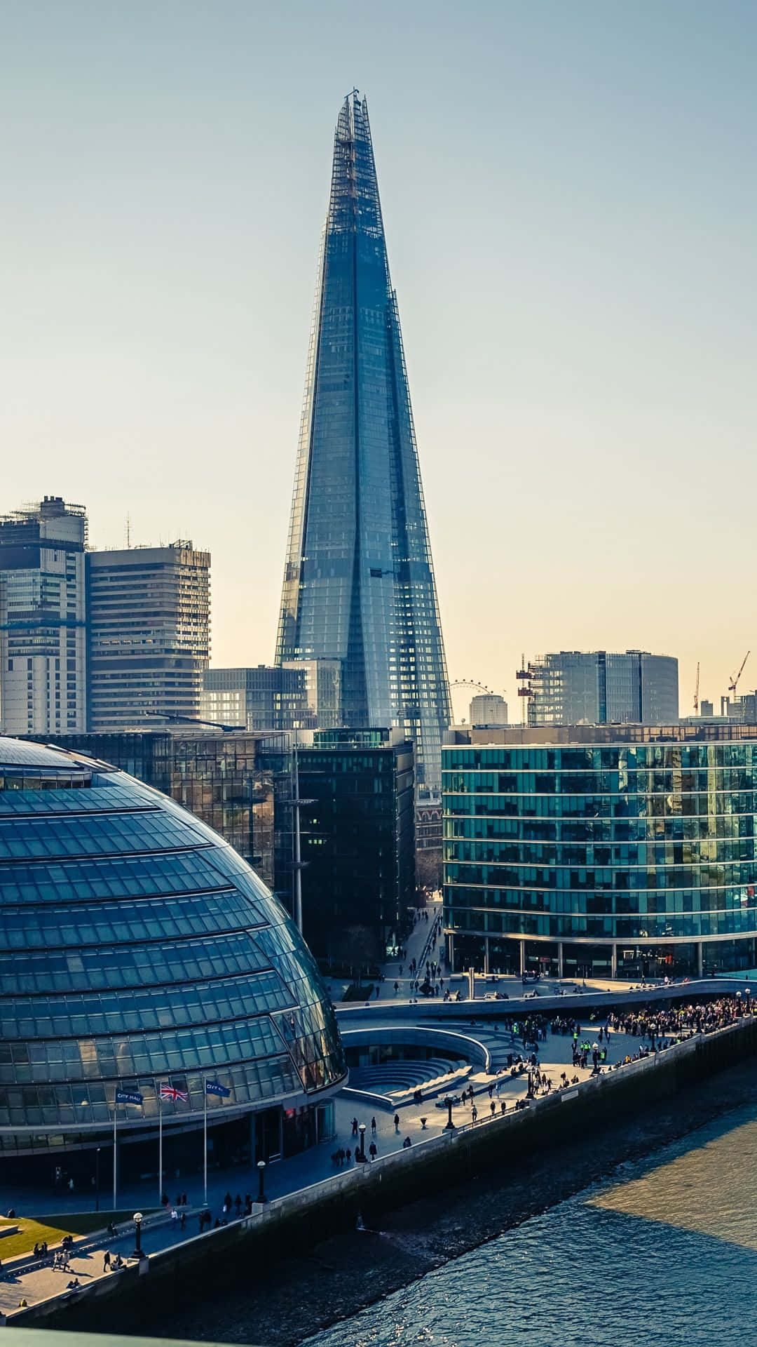 London iPhone 桌布 壁紙 — 碎片大廈摩天大樓在黃金時段聳立於倫敦的現代天際線之上，擁有反光玻璃幕牆和熙來攘往的河濱長廊。