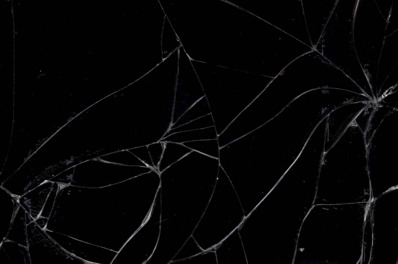 Netflix 桌布 壁紙 — 碎裂玻璃的特寫，帶有複雜的白色裂紋，背景為純黑色。