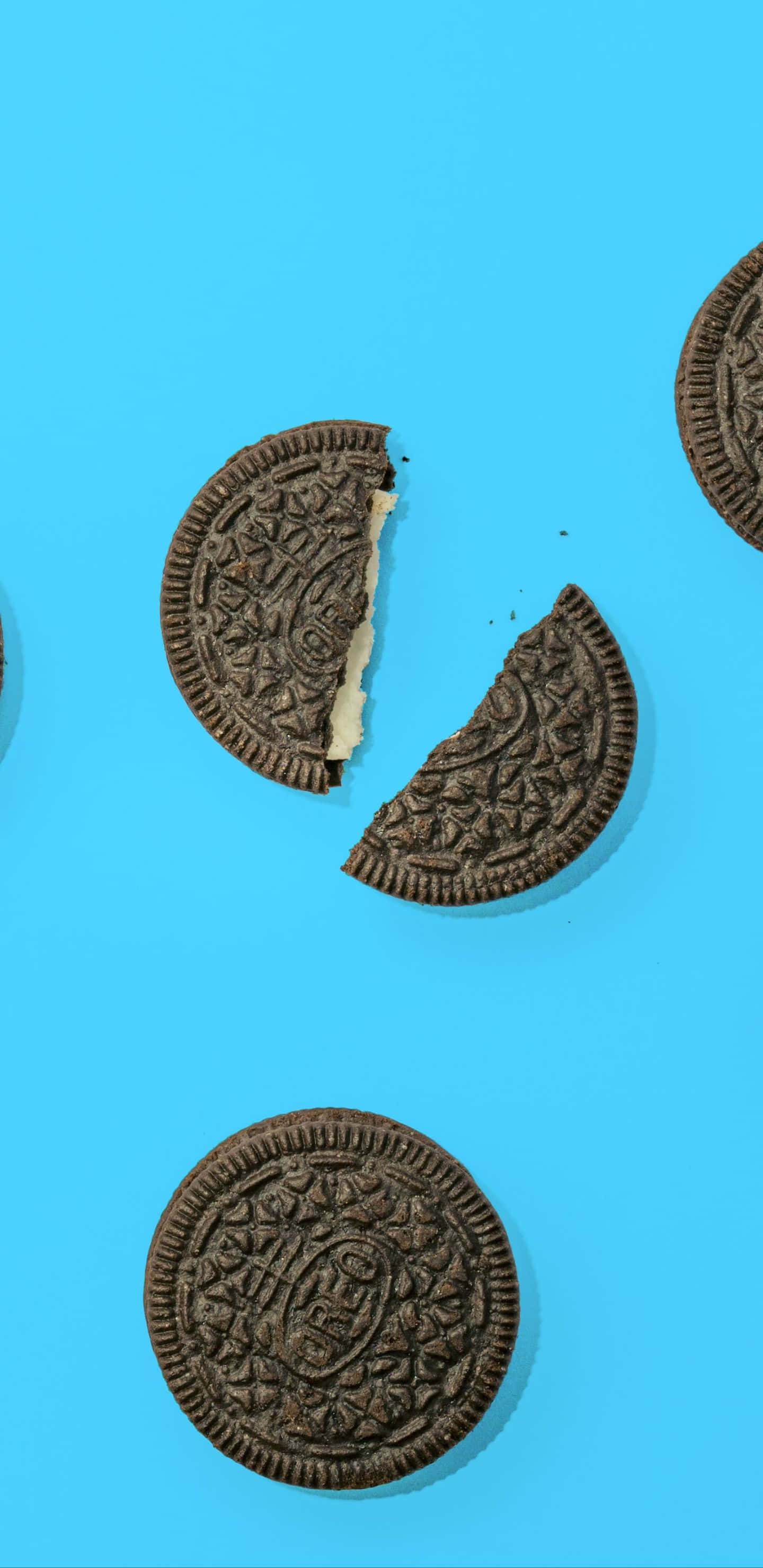 oreo 桌布 壁紙 — 碎裂的Oreo餅乾帶有奶油夾心，散落在明亮的藍色背景上。