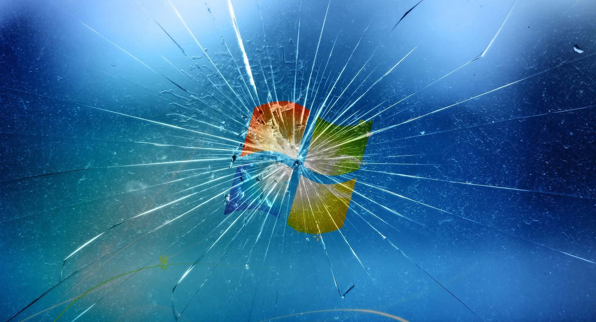 cracked 桌布 壁紙 — 碎裂的玻璃表面，中央有一個破裂的Windows標誌，背景為深藍色漸變。