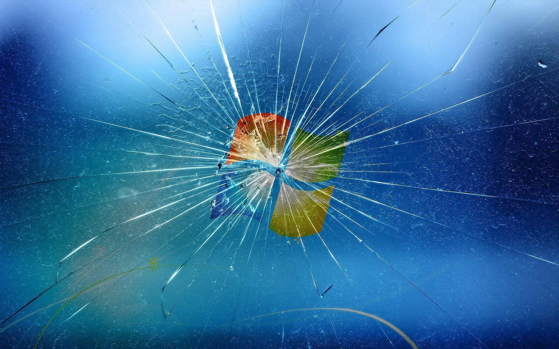 broken monitor 桌布 壁紙 — 碎裂的玻璃表面，中心有一個破裂的Microsoft標誌，背景為藍色漸層。