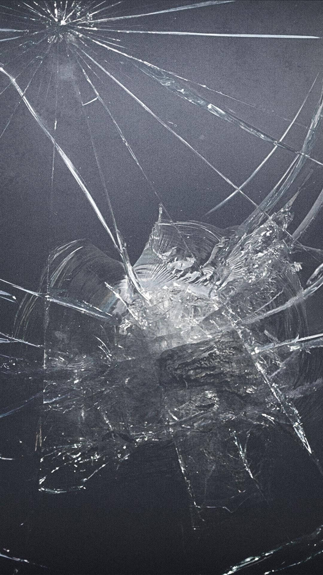 cracked 桌布 壁紙 — 碎裂的玻璃表面，從中央撞擊點向外輻射出複雜裂紋，背景為深色。