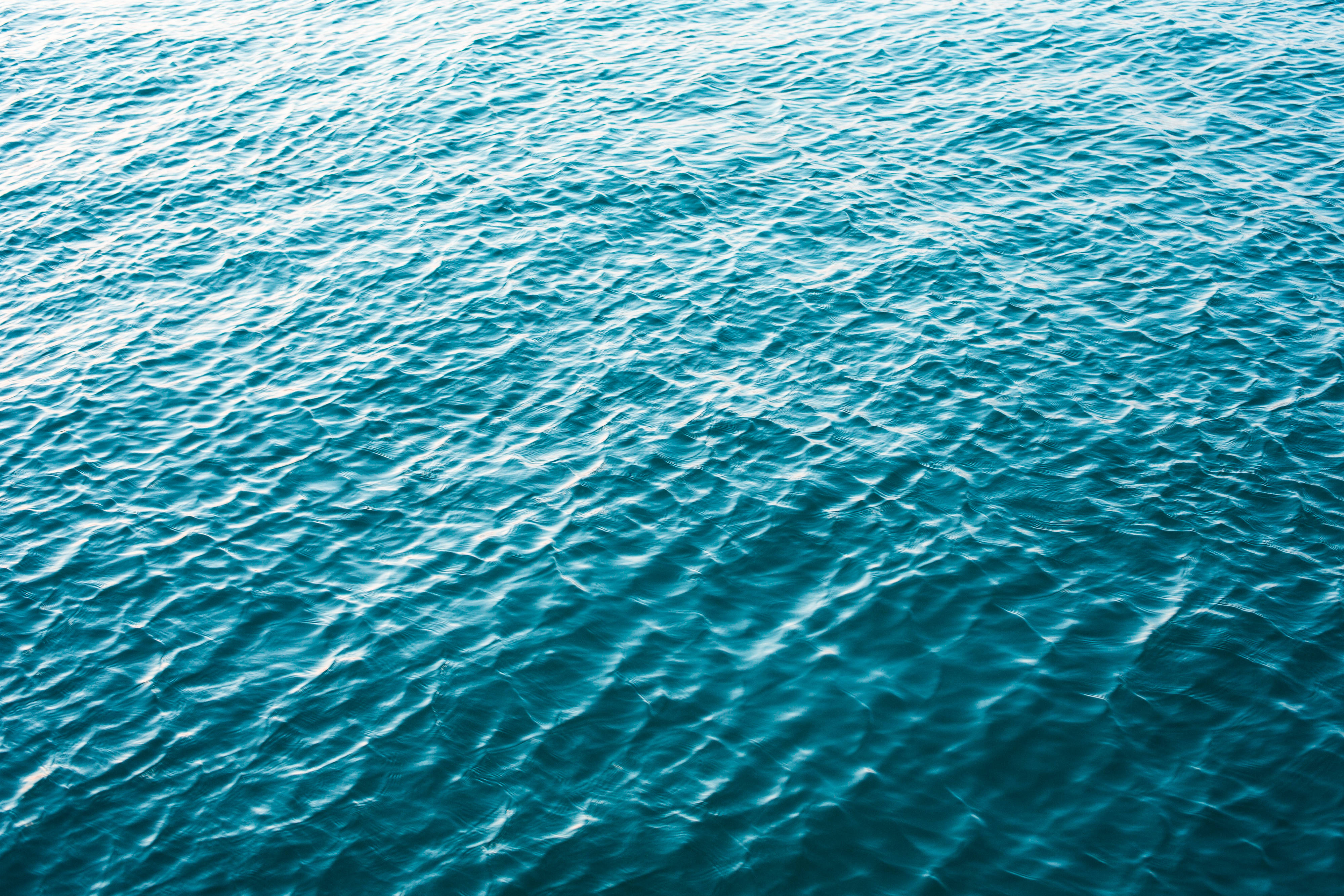 海洋 桌布 壁紙 — 碧綠海水泛起漣漪的近景，陽光在溫柔的波浪上閃爍。