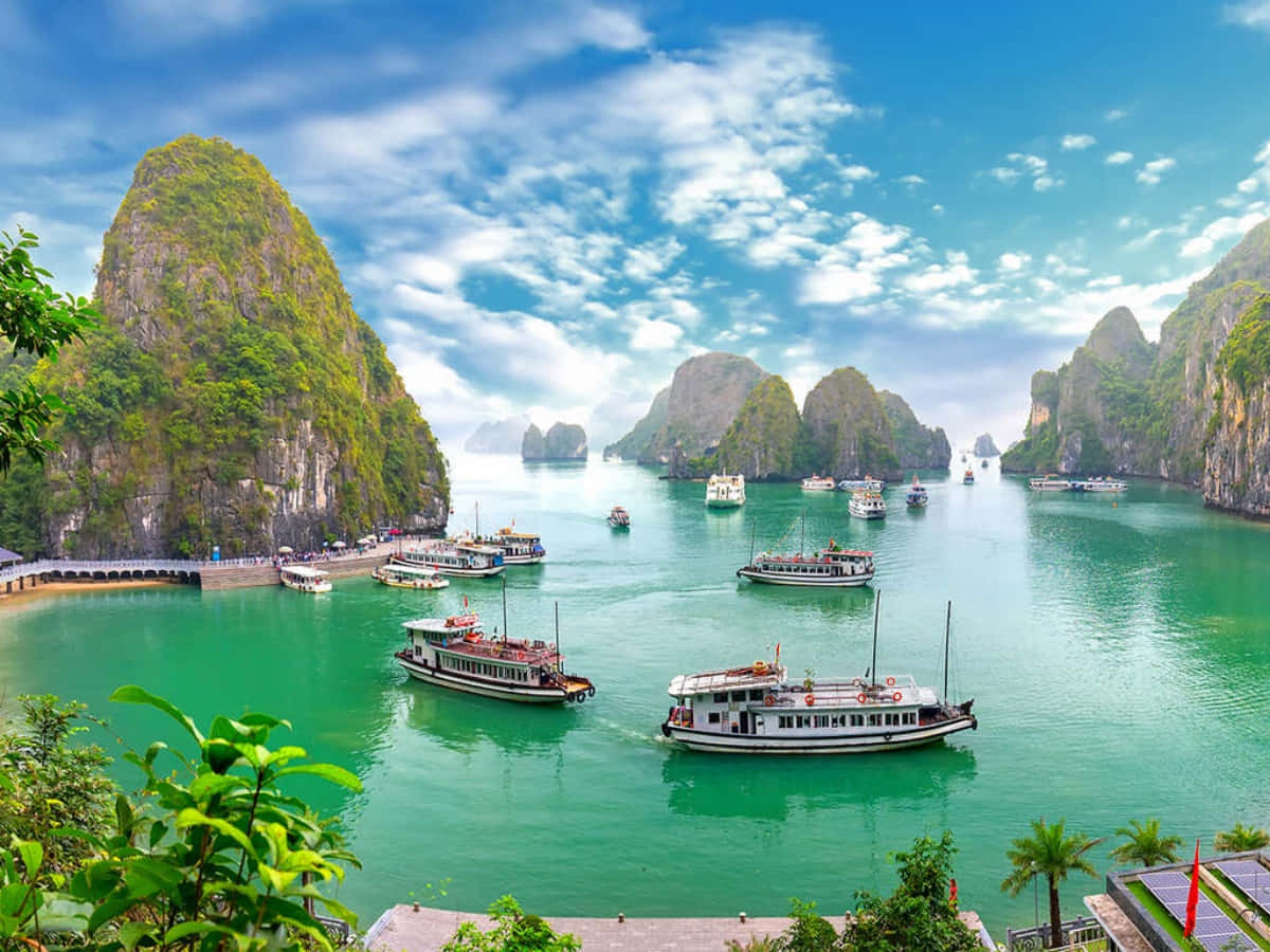 越南 桌布 壁紙 — 碧綠海水環抱石灰岩喀斯特地貌，觀光船在湛藍天空下穿梭於下龍灣。
