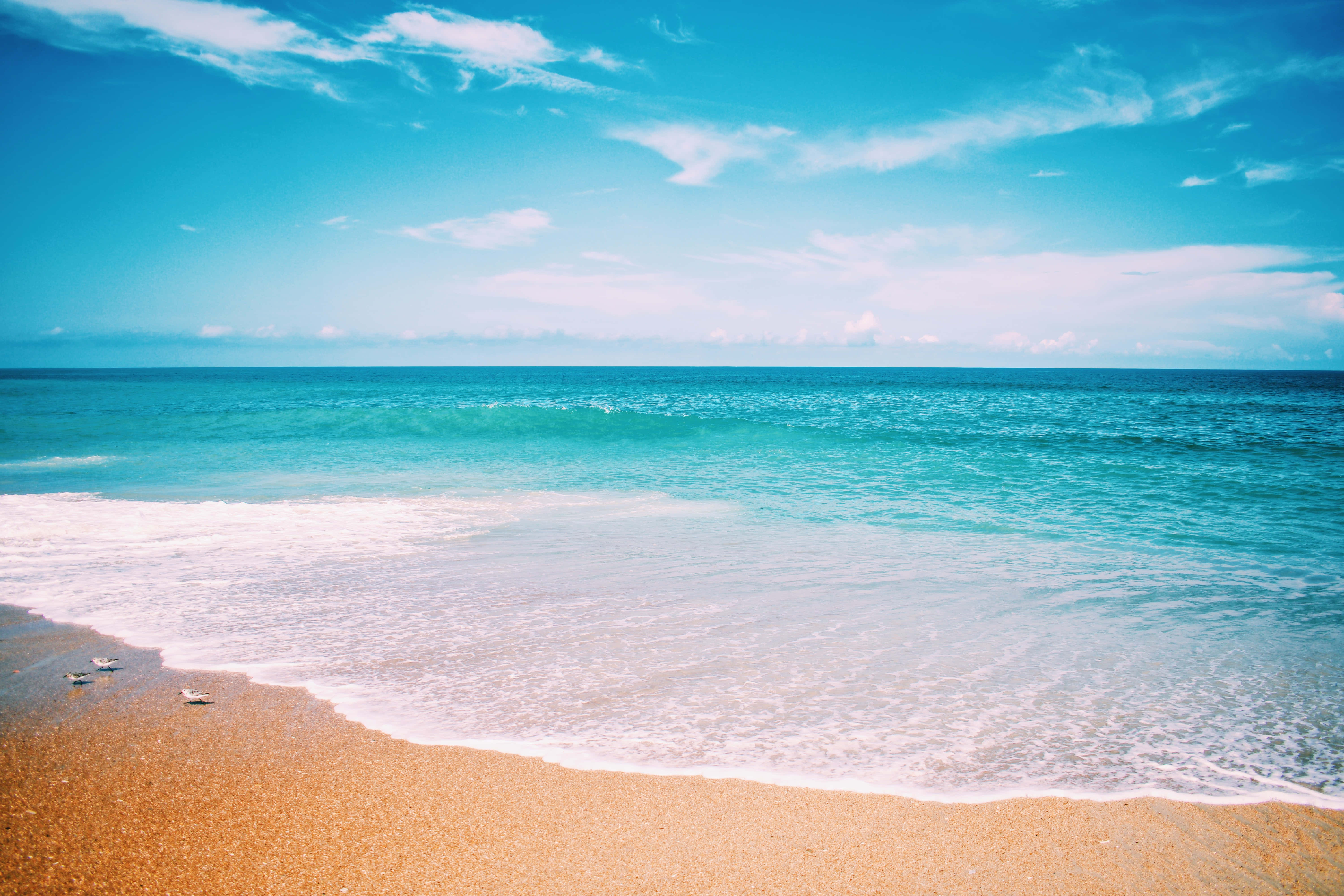 Beautiful Beach 桌布 壁紙 — 碧綠的海浪輕輕拍打著金色沙灘，天空湛藍，飄著幾縷薄雲。