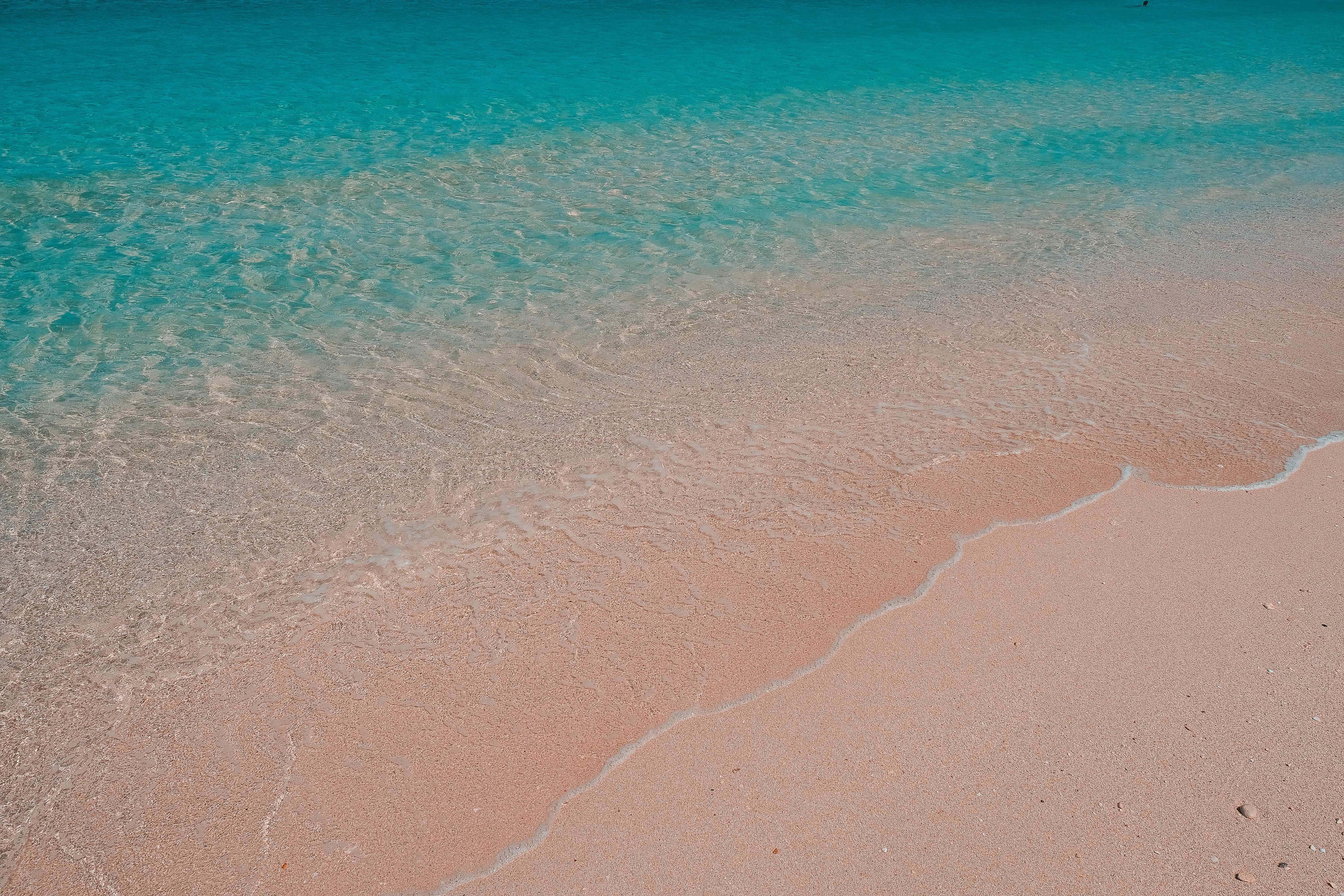 Twitter Header 桌布 壁紙 — 碧綠色的海浪輕輕拍打柔軟的粉紅色沙灘，構成寧靜的熱帶海灘場景。