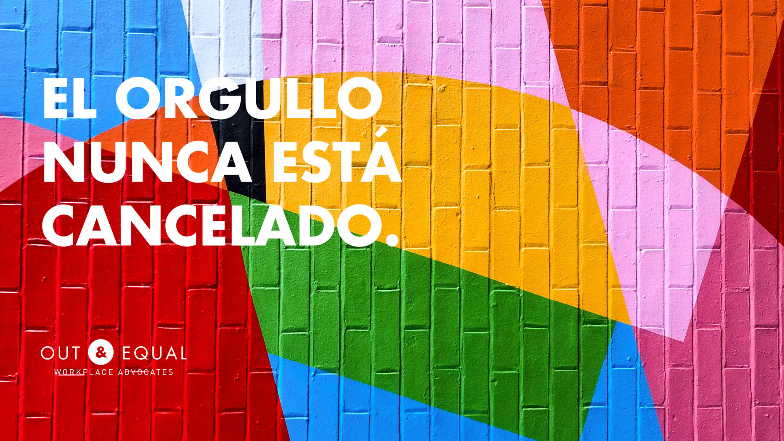 Spanish 桌布 壁紙 — 磚牆上充滿活力的彩虹壁畫，粗體白色文字宣佈驕傲從未被取消。