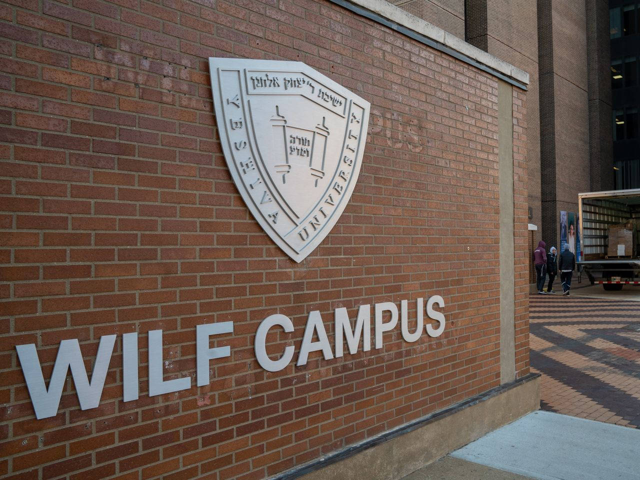 Architecture 桌布 壁紙 — 磚牆特寫，上有白色盾牌標誌及「WILF CAMPUS」字樣，在明亮日光下拍攝。