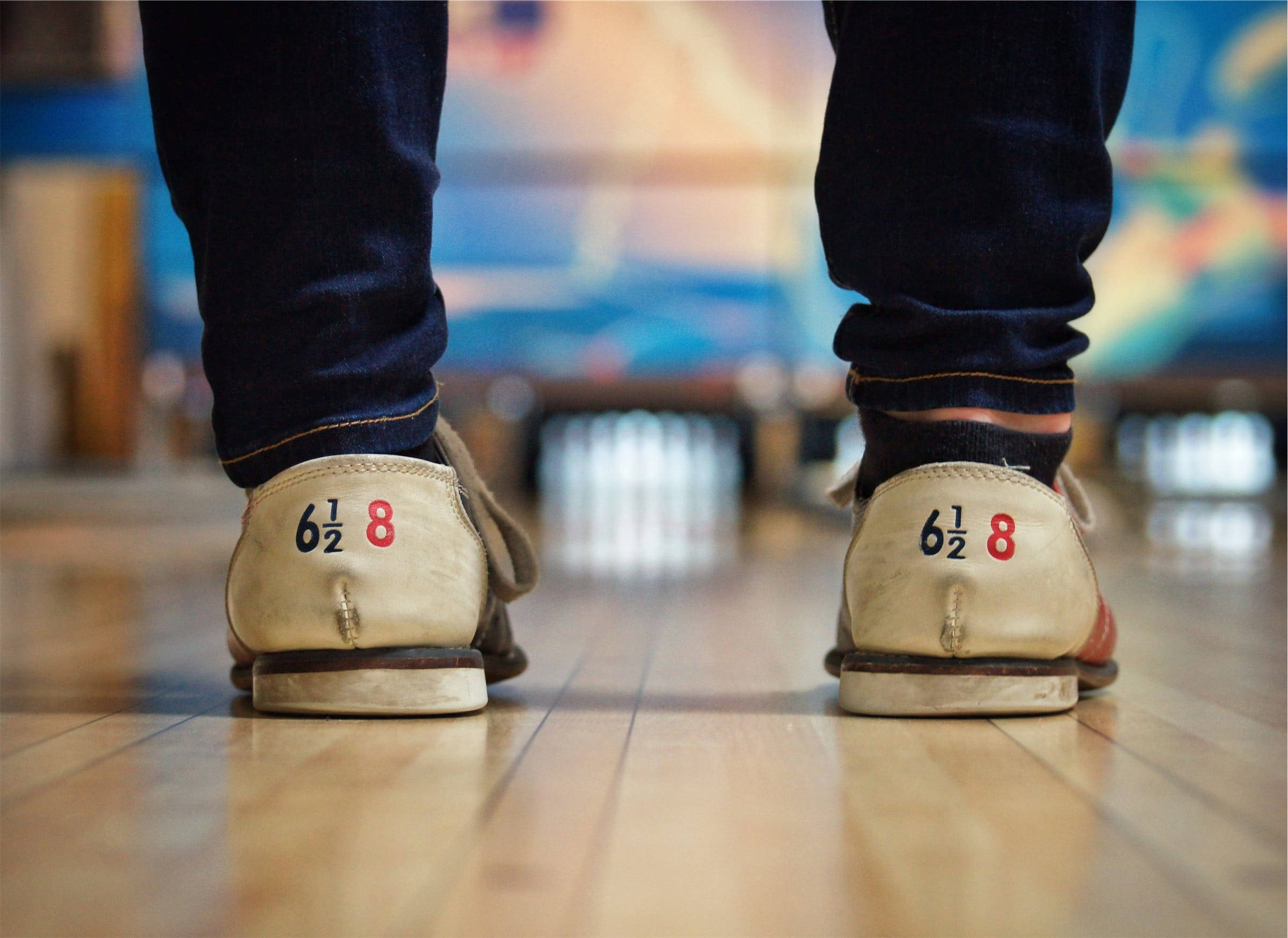 Bowling 桌布 壁紙 — 磨損保齡球鞋的特寫，鞋跟上有數字，站在拋光木製球道上，面向球瓶。
