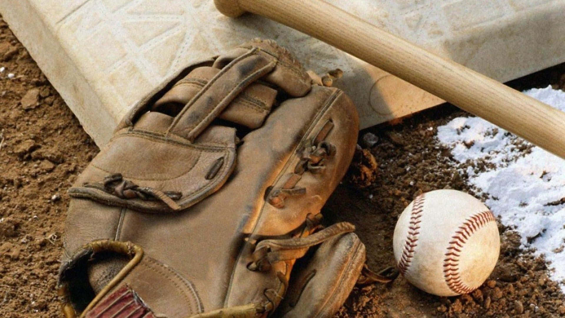 baseball bat 桌布 壁紙 — 磨損的棒球手套、球棒和球放在本壘板附近的泥土上，帶有融化的雪塊。