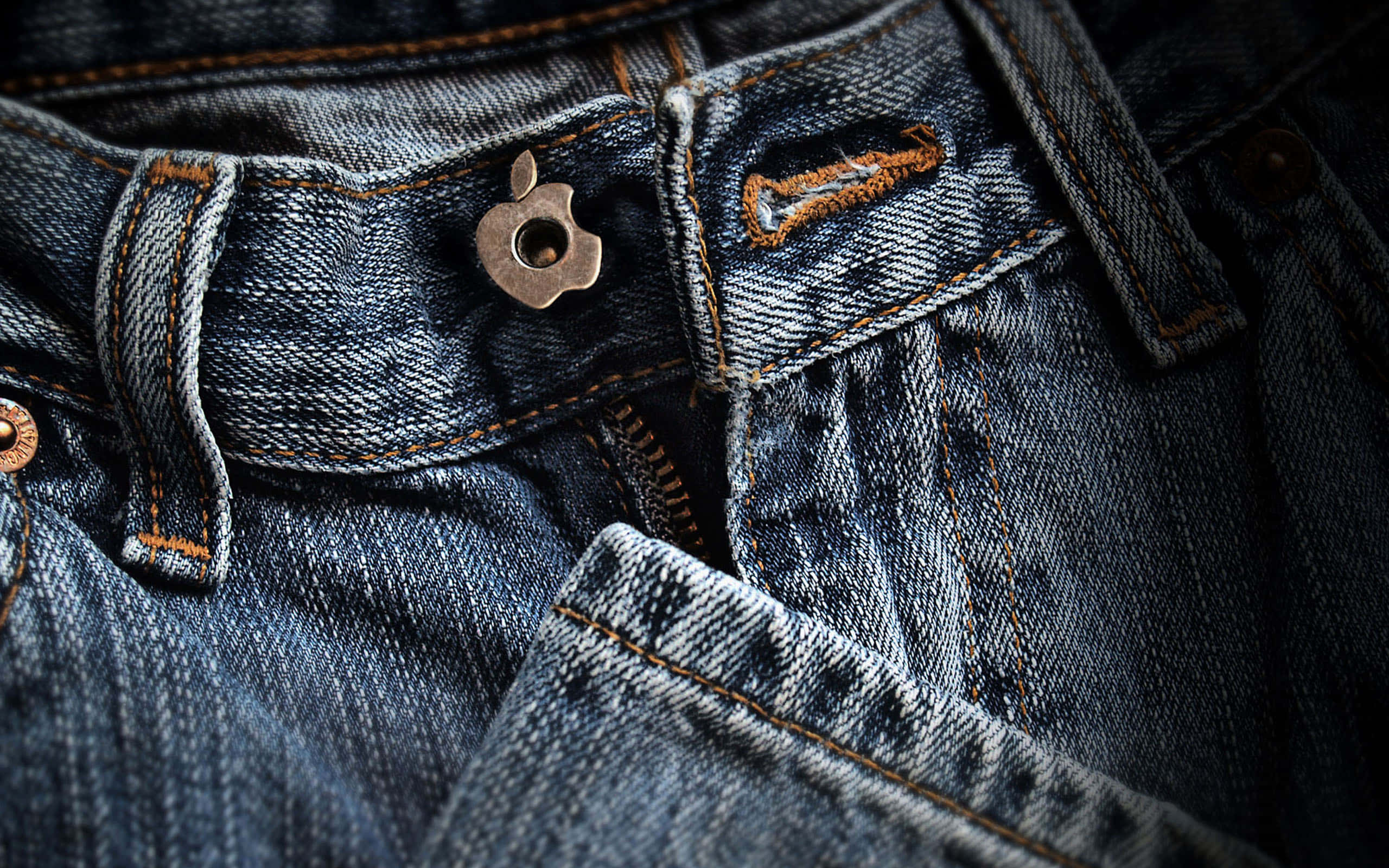 Denim 桌布 壁紙 — 磨損的藍色牛仔褲近距離特寫，帶有金屬蘋果鈕扣和橙色縫線。