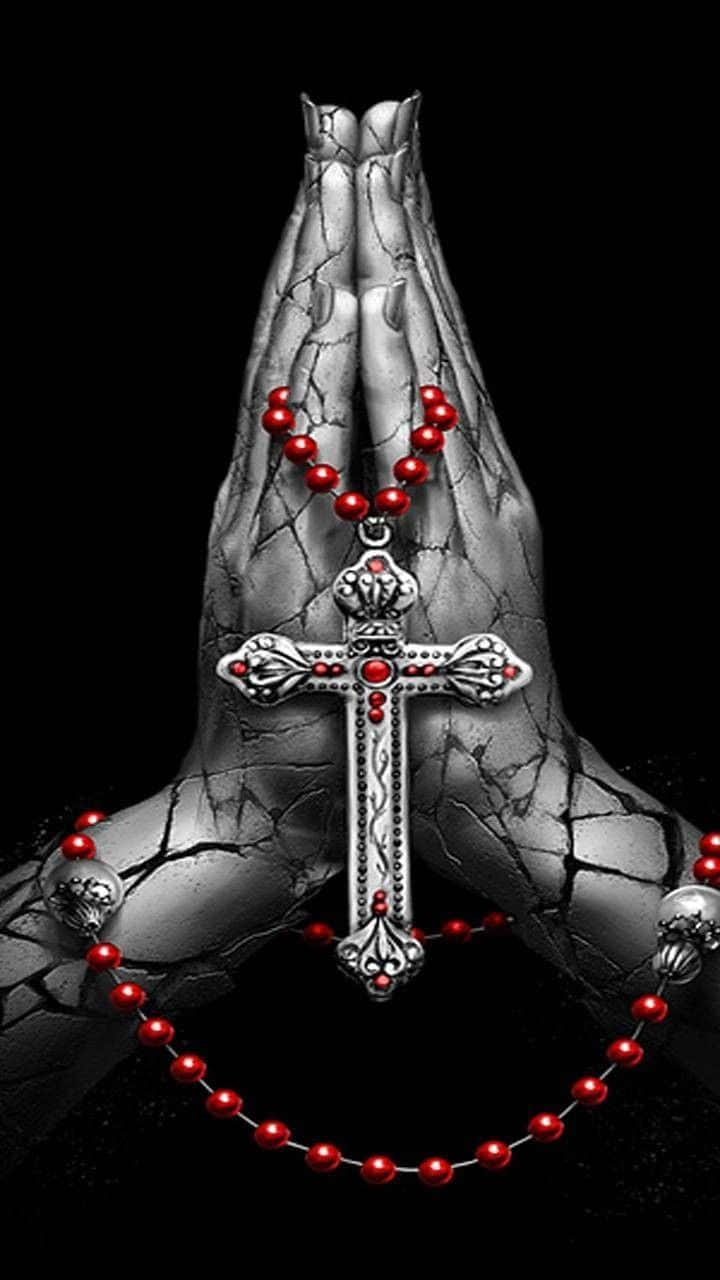 Praying Hands 桌布 壁紙 — 祈禱中緊握的雙手，在破裂的黑色背景上握著銀色十字架和紅色玫瑰經念珠。