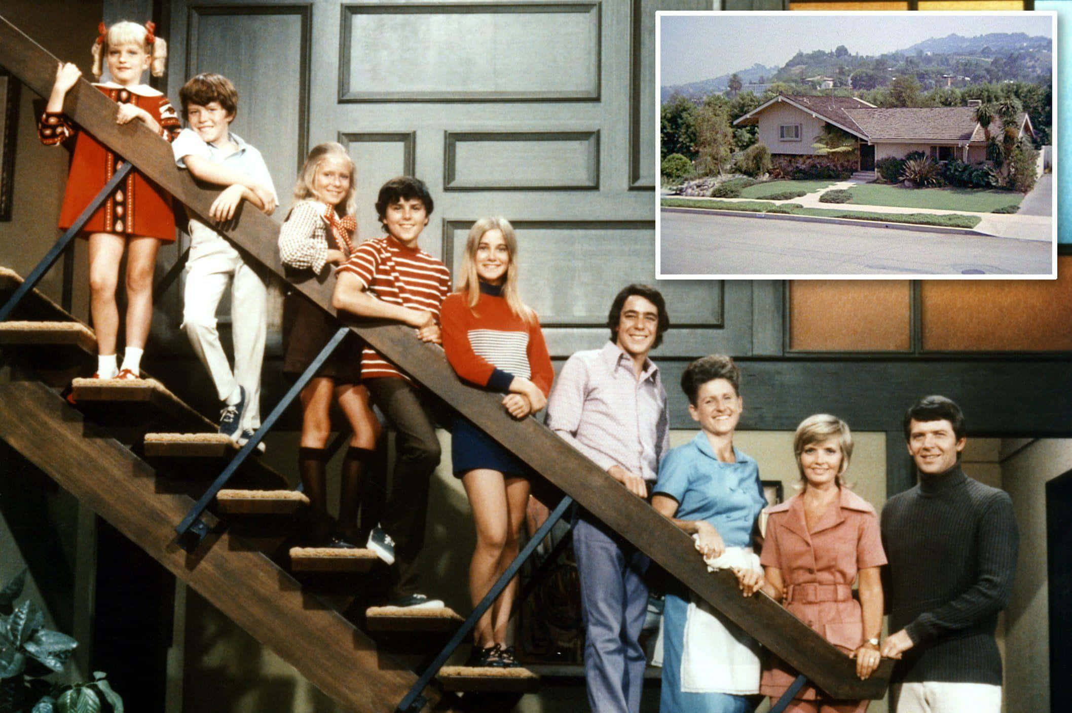 Brady Bunch Zoom 桌布 壁紙 — 《神仙家庭》的演員在木樓梯上擺姿勢，背景是他們真實家園的照片。