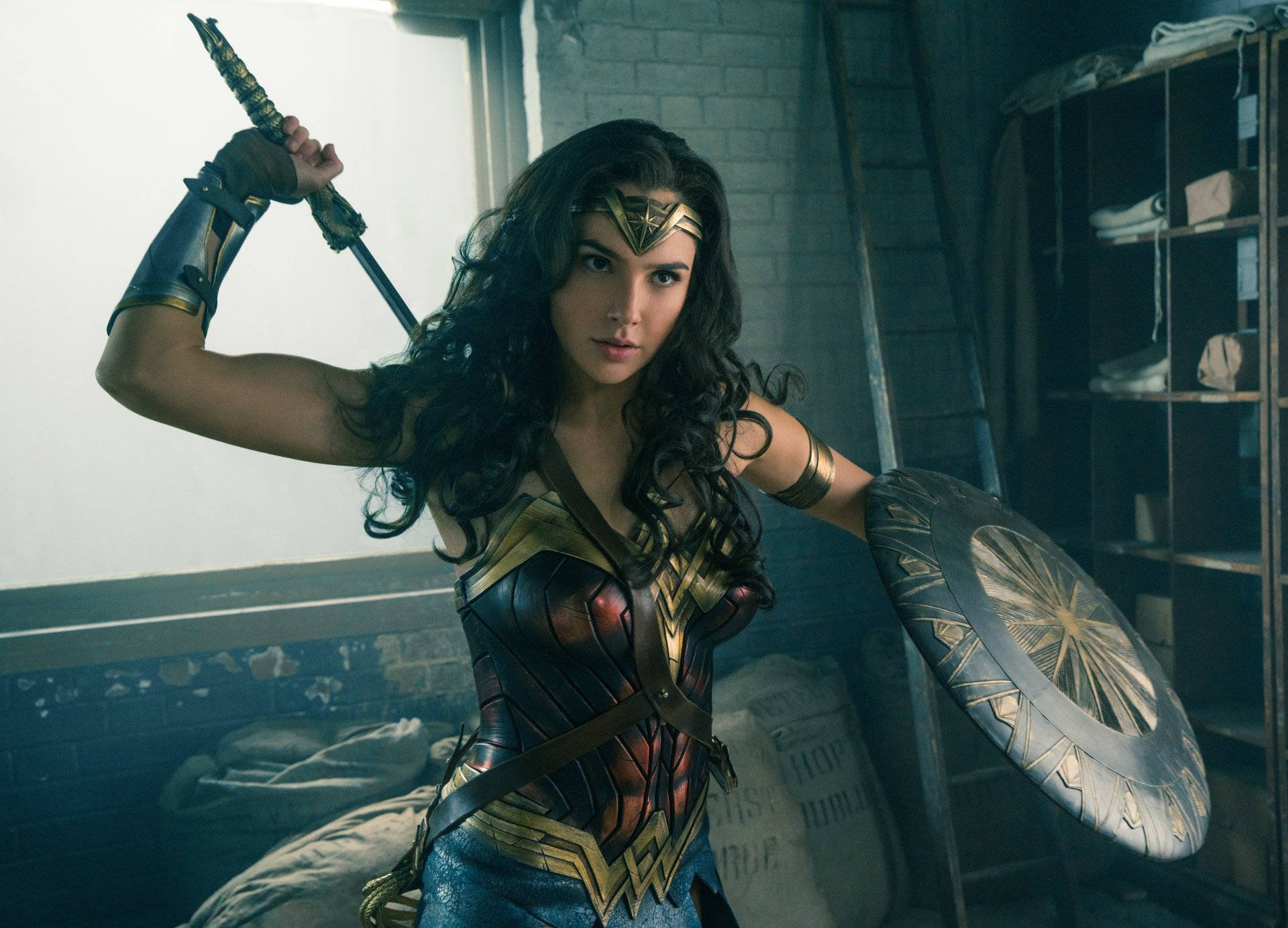 Wonder Woman 桌布 壁紙 — 神力女超人在骯髒的倉庫中手持劍盾，帶著強烈的決心站立。