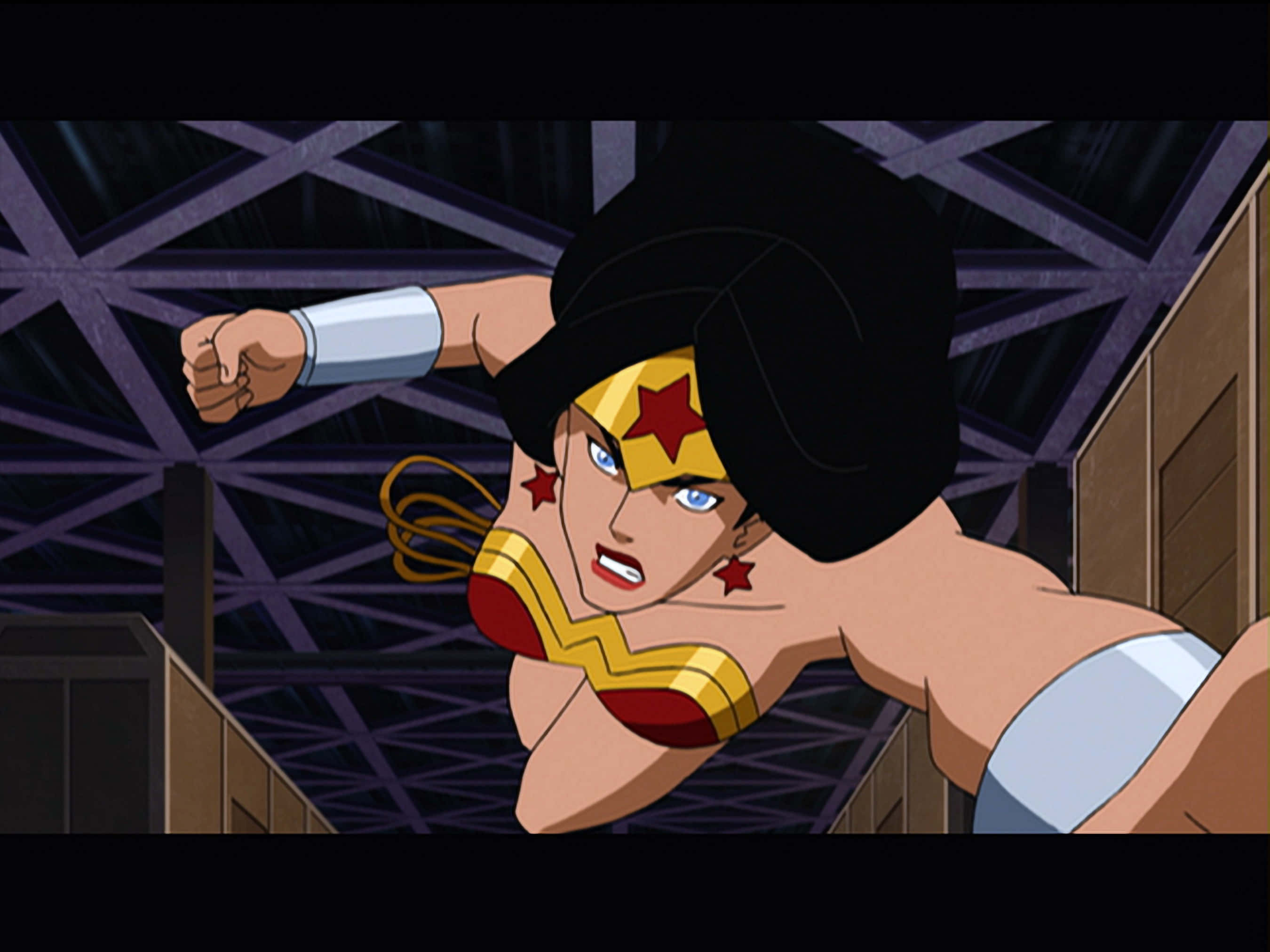 Justice League Doom 桌布 壁紙 — 神力女超人擺出動感十足的動作姿勢，握緊拳頭，表情堅定，背景是黑暗的工業天花板。