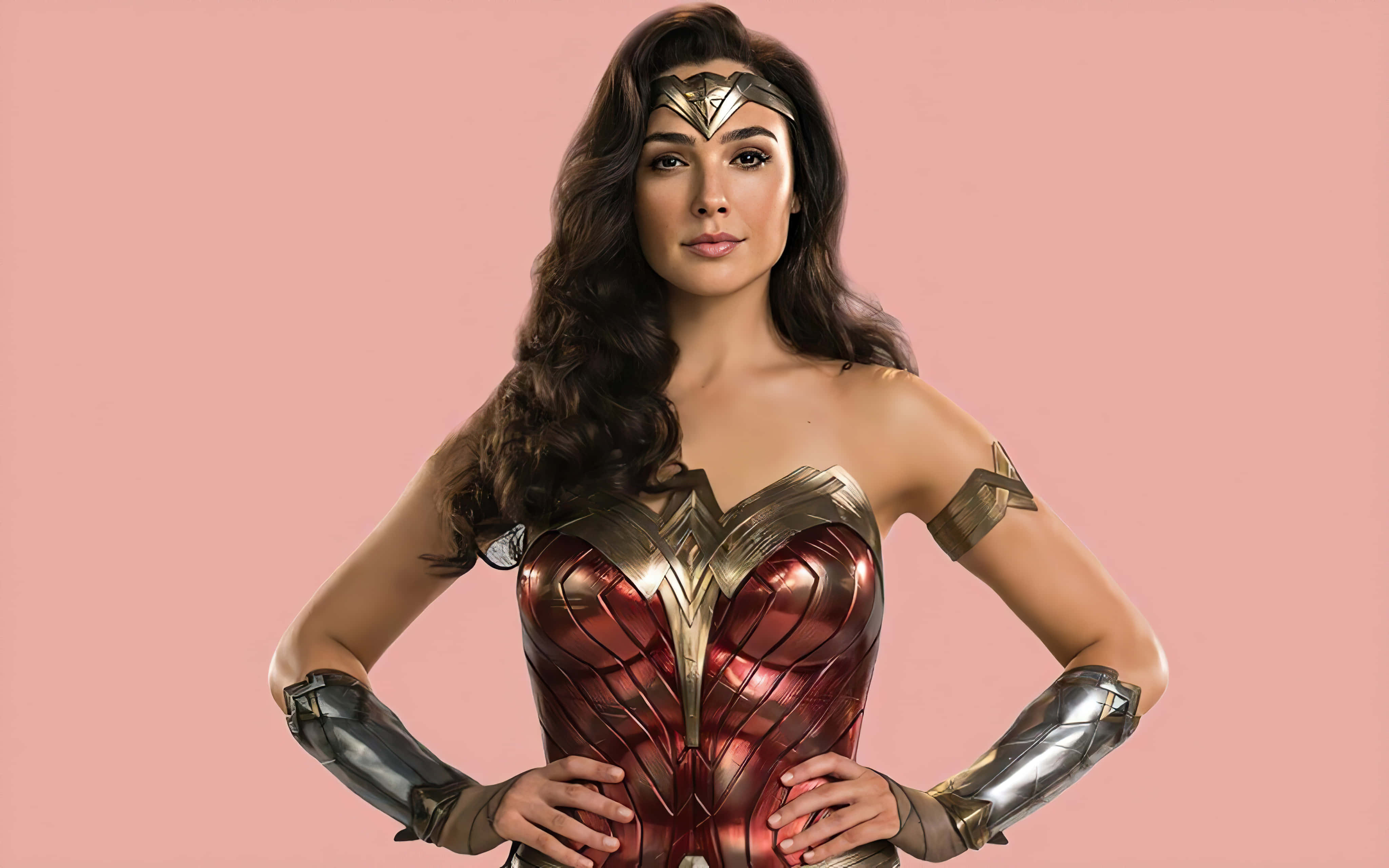 Wonder Woman 桌布 壁紙 — 神力女超人穿著標誌性的紅金銀盔甲，自信地站在柔和的粉紅色背景前。