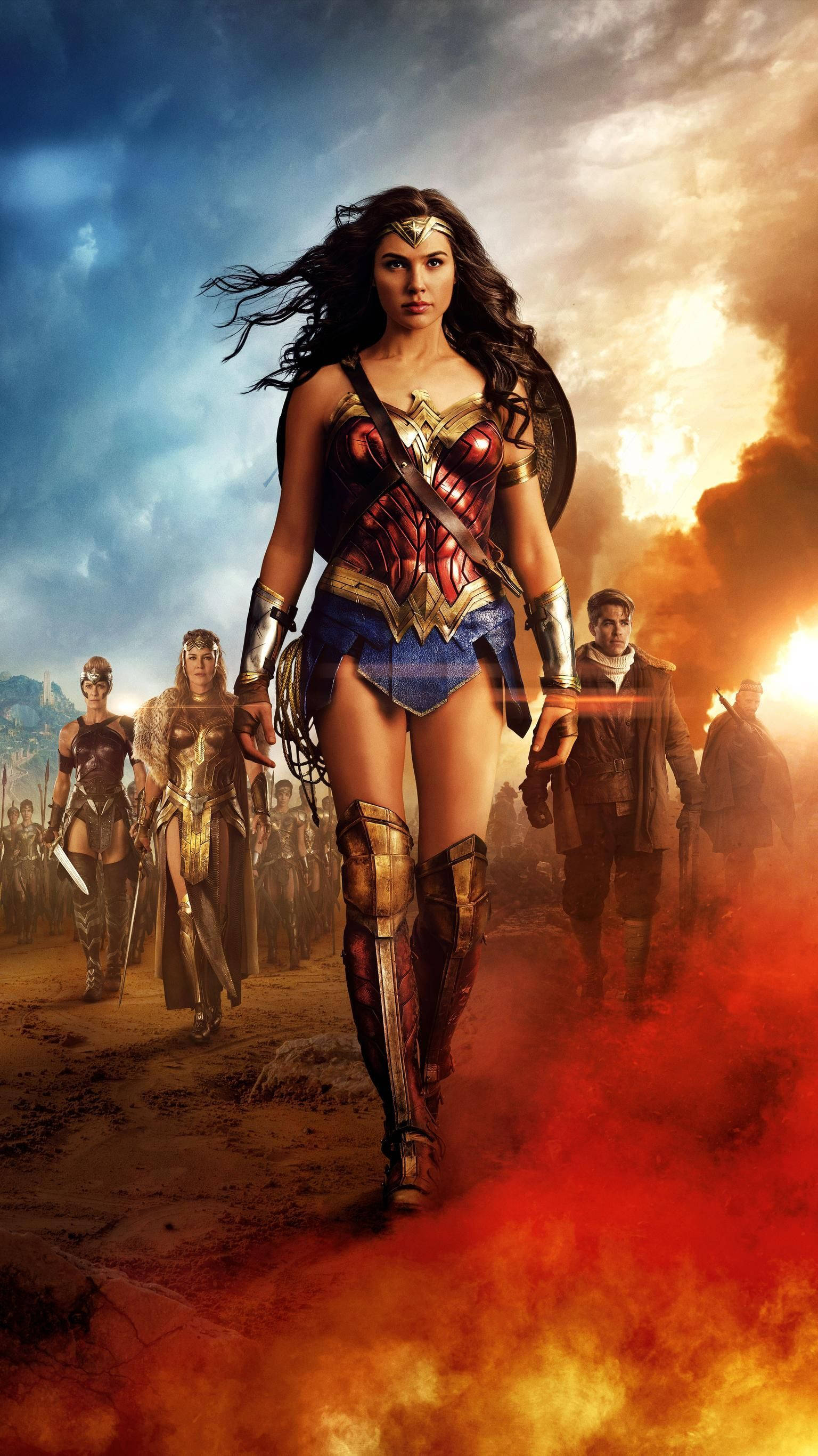 Wonder Woman 1984 桌布 壁紙 — 神力女超人穿過火熱的煙霧向前邁進，身後是她的亞馬遜軍隊，背景是戲劇性的天空。