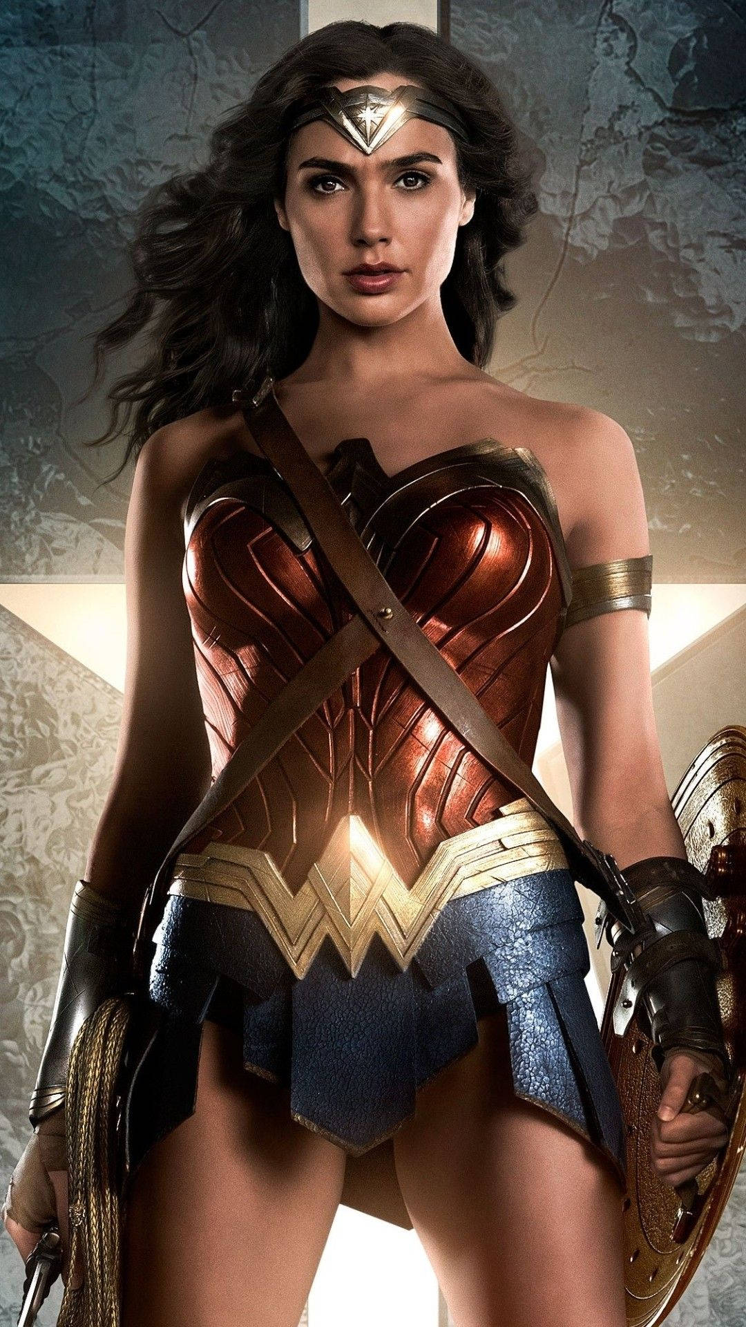 Wonder Woman 桌布 壁紙 — 神力女超人自信地站立，身穿標誌性的青銅和金色盔甲，手持盾牌和真言套索，背景是破裂的石牆。